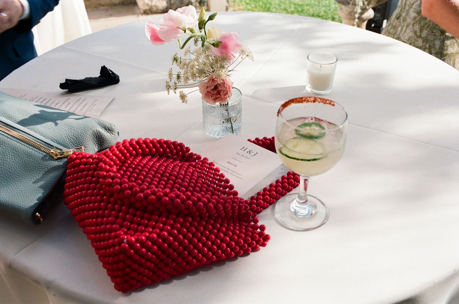 Red knitted napkin on white tablecloth with glass vase centerpiece.
