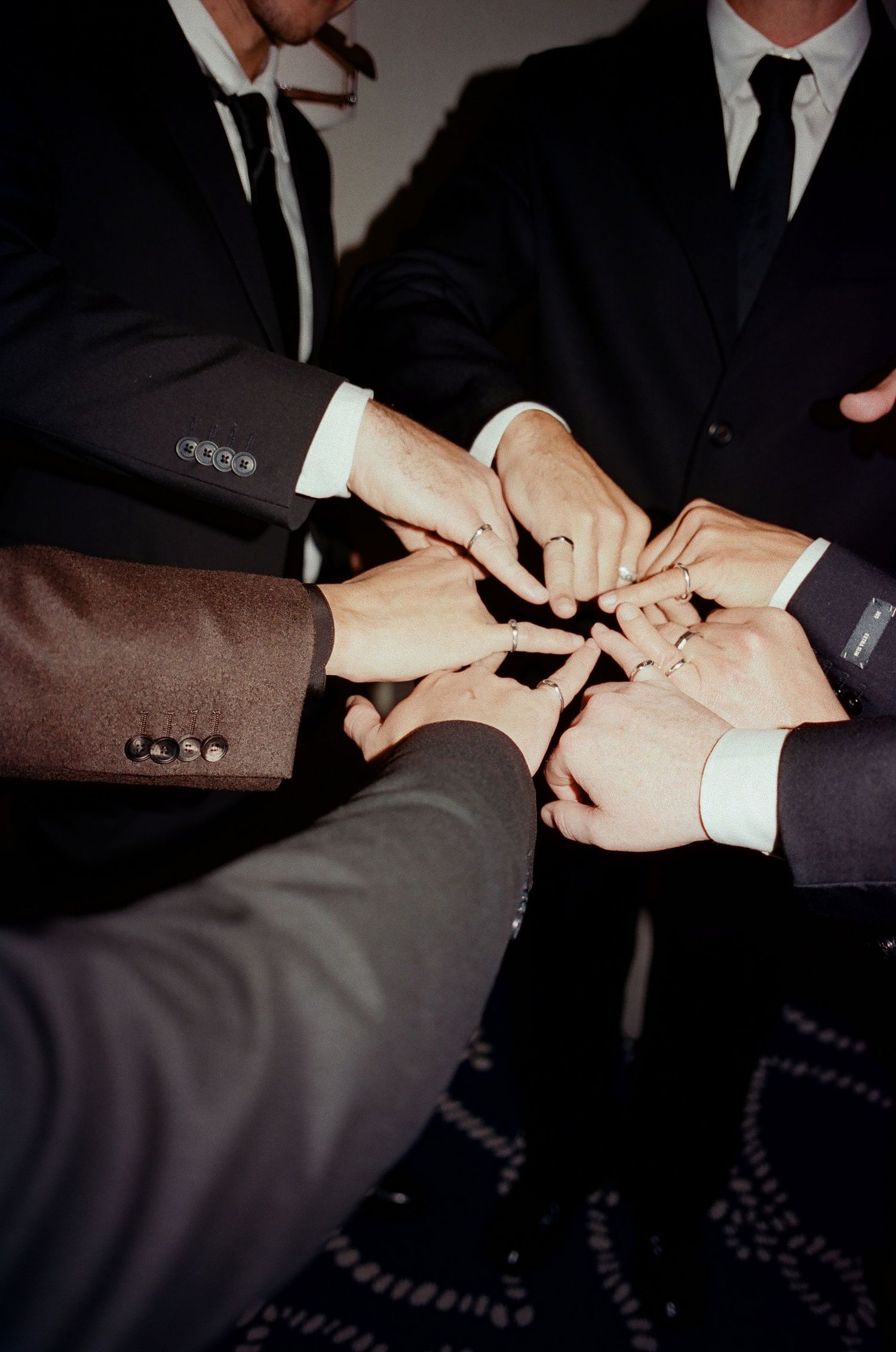 A sequence of hands in formal suits performing a secret handshake ritual in dark lighting.