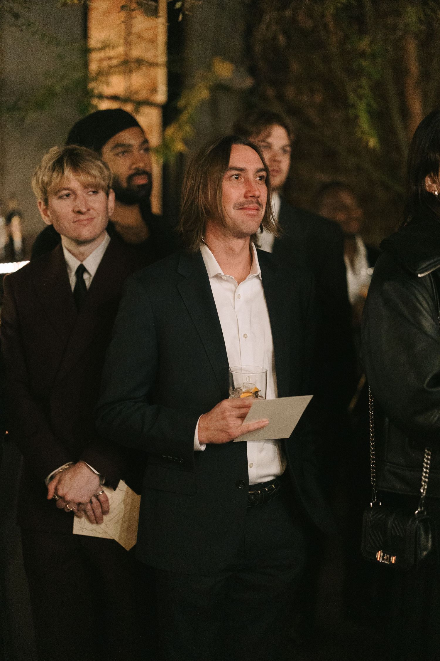 Wedding guests in formal wear mingle during the evening celebration.