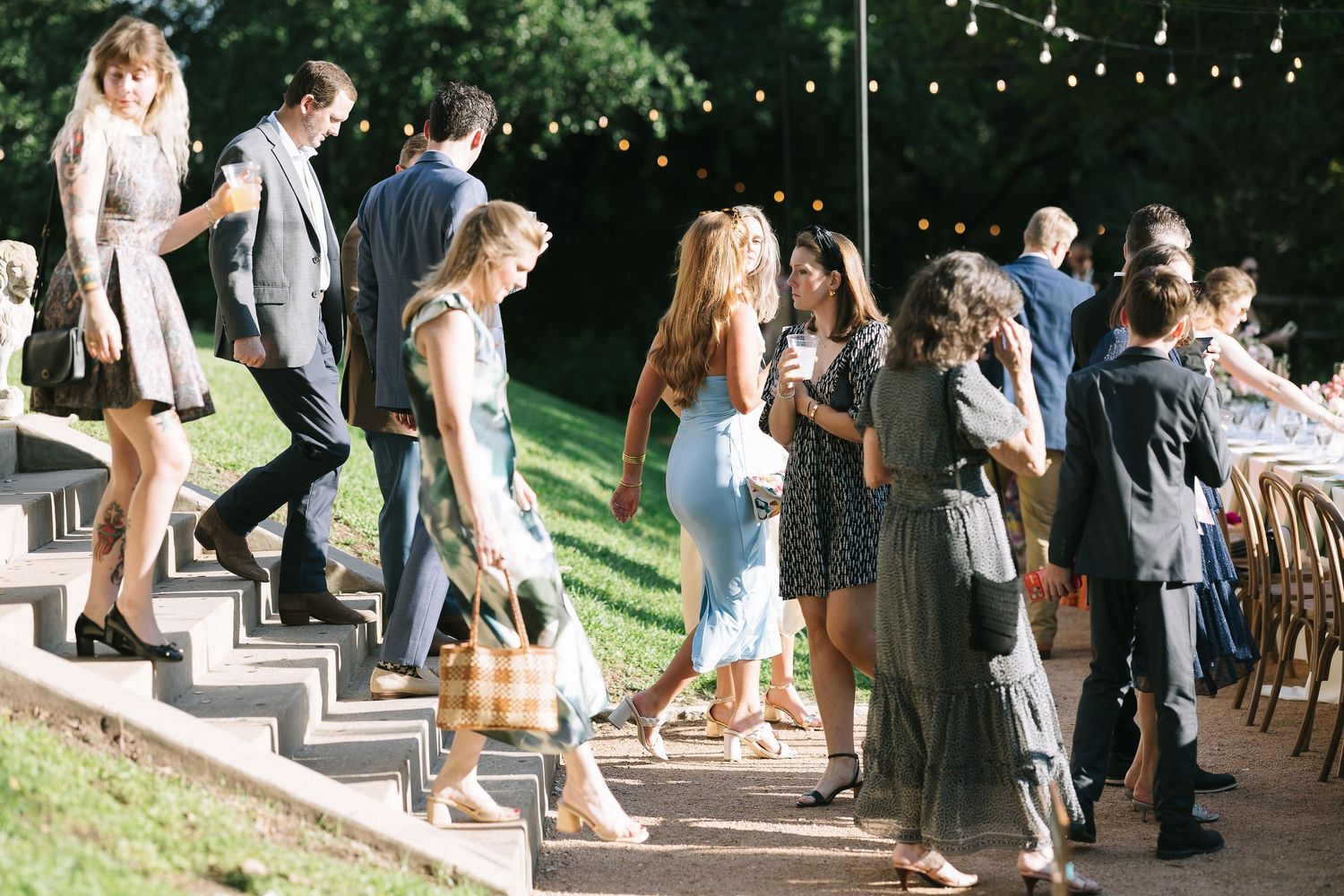 Wedding guests mingling on outdoor stone steps during a garden reception.