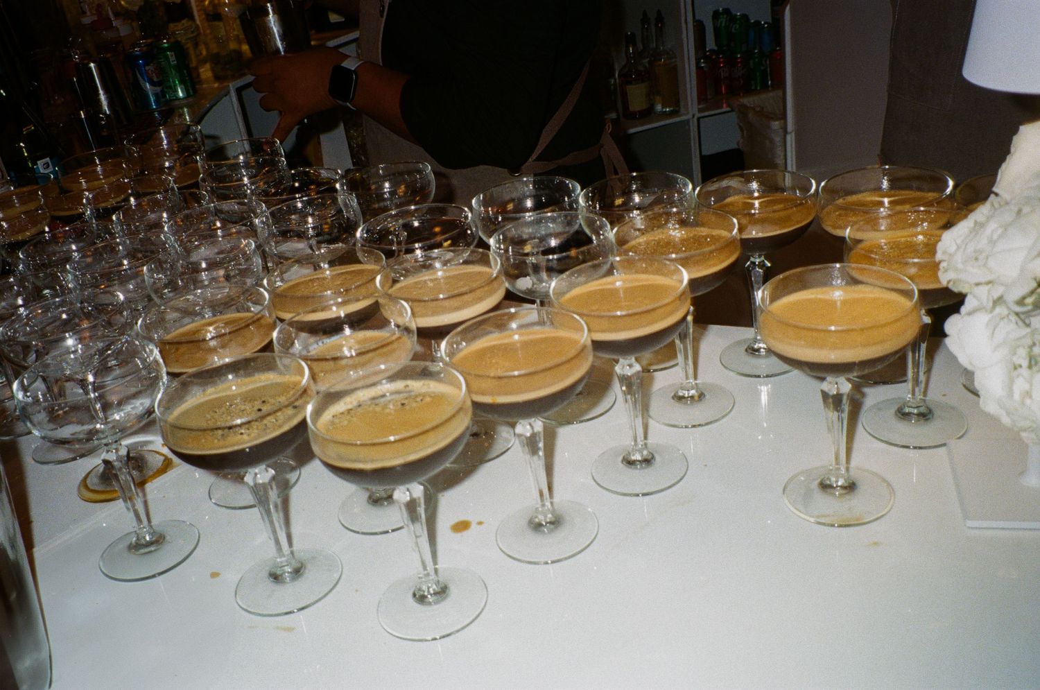 Long row of empty champagne glasses lined up on a white tablecloth.