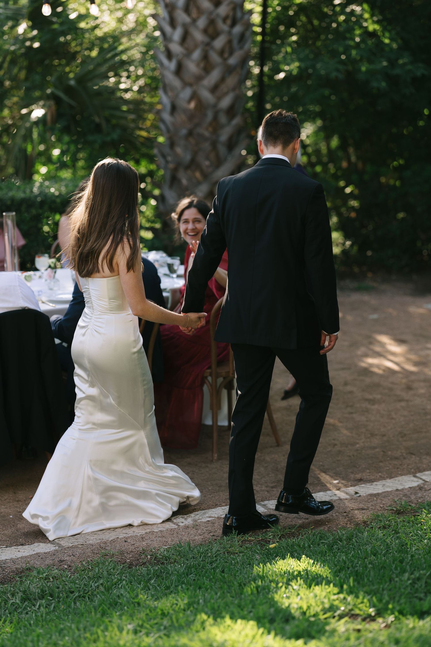 Wedding guests seated on grass during an outdoor garden ceremony.