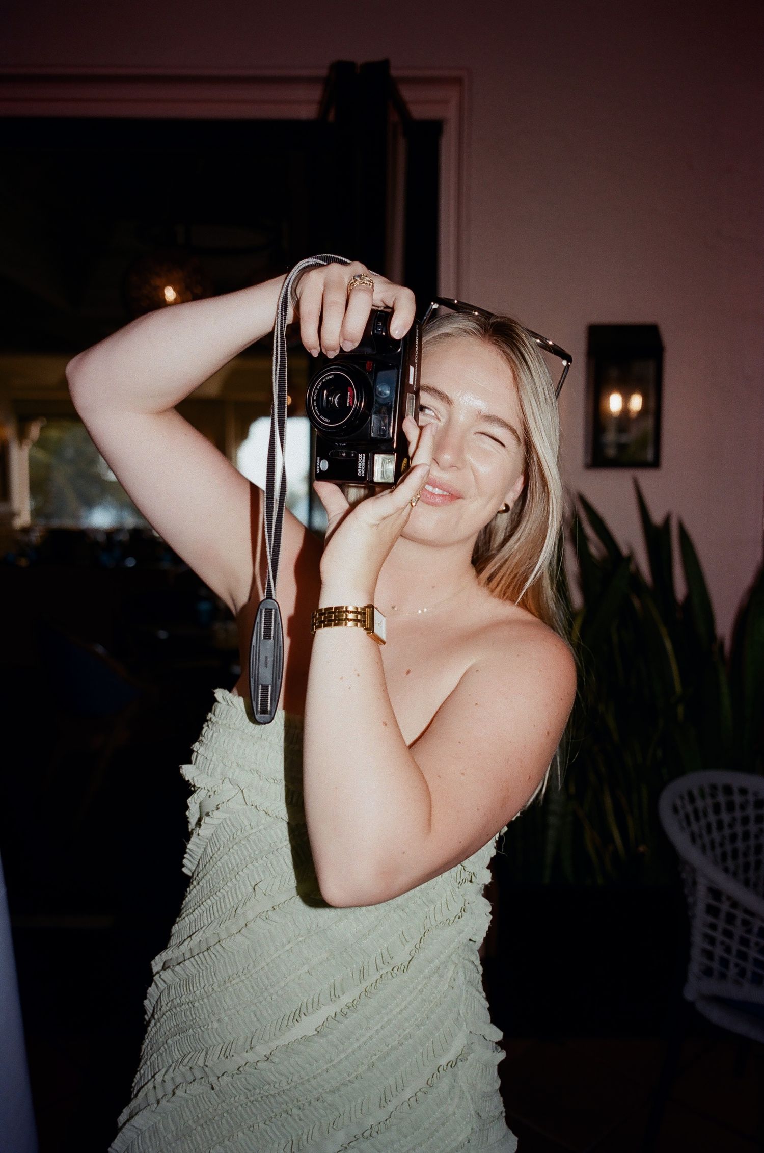 A person in a mint green dress taking photos with a vintage camera at a party.