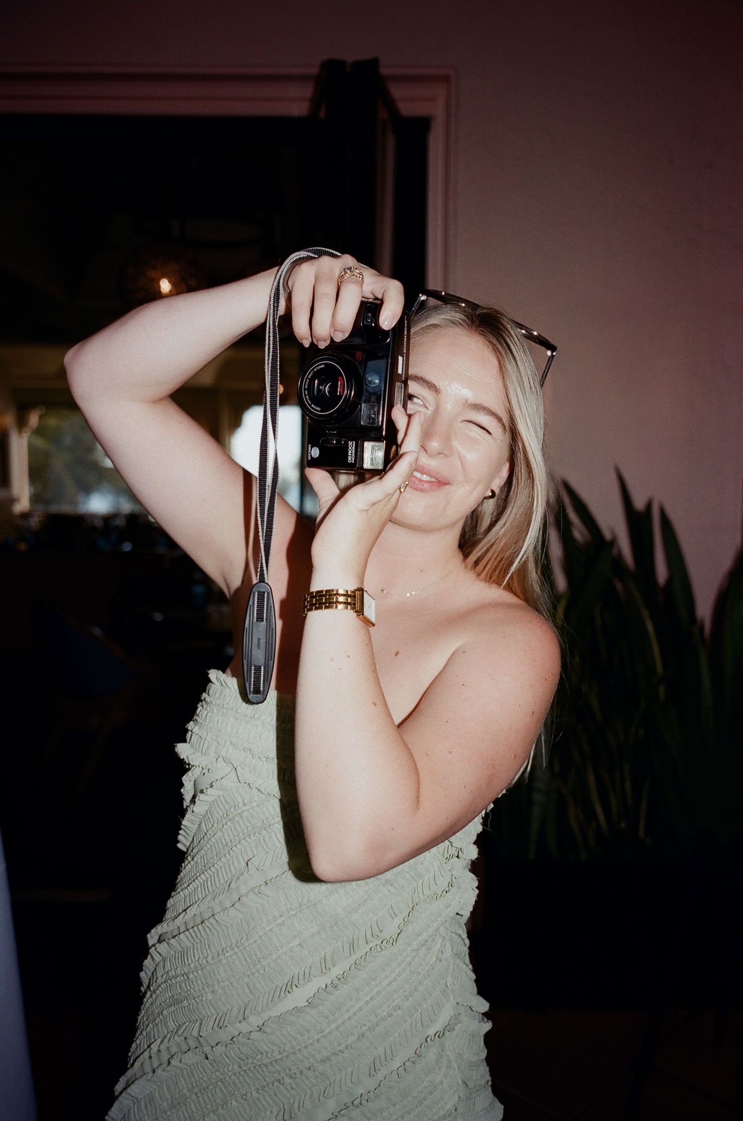 A photographer in a light dress takes a picture at an evening event.