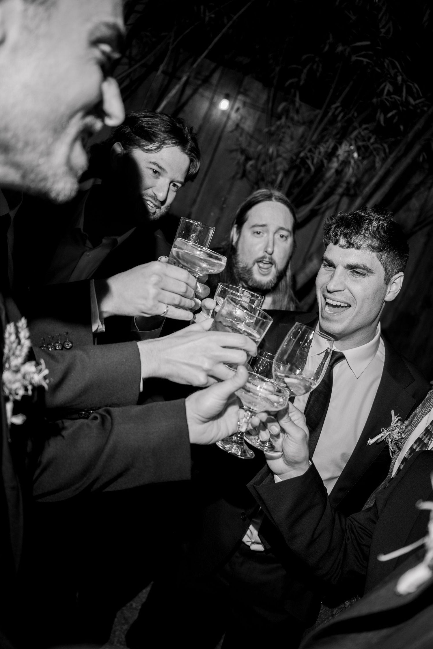 Friends raise glasses in a toast during a nighttime celebration.