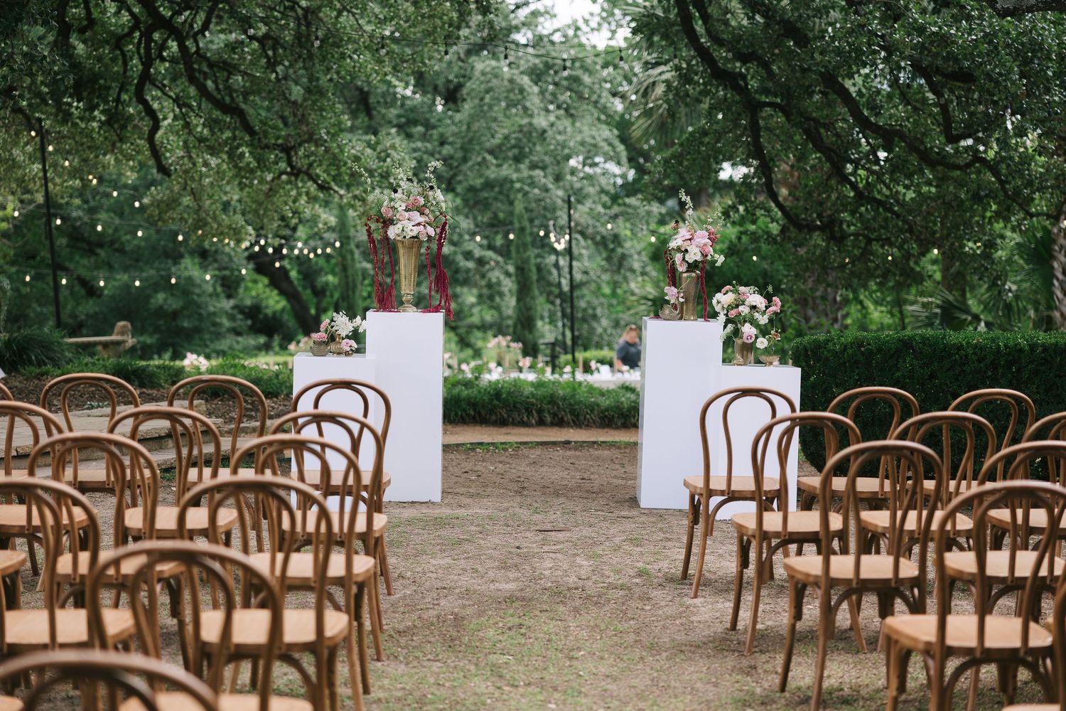 Rustic wooden chairs set up in rows for an outdoor garden wedding ceremony.