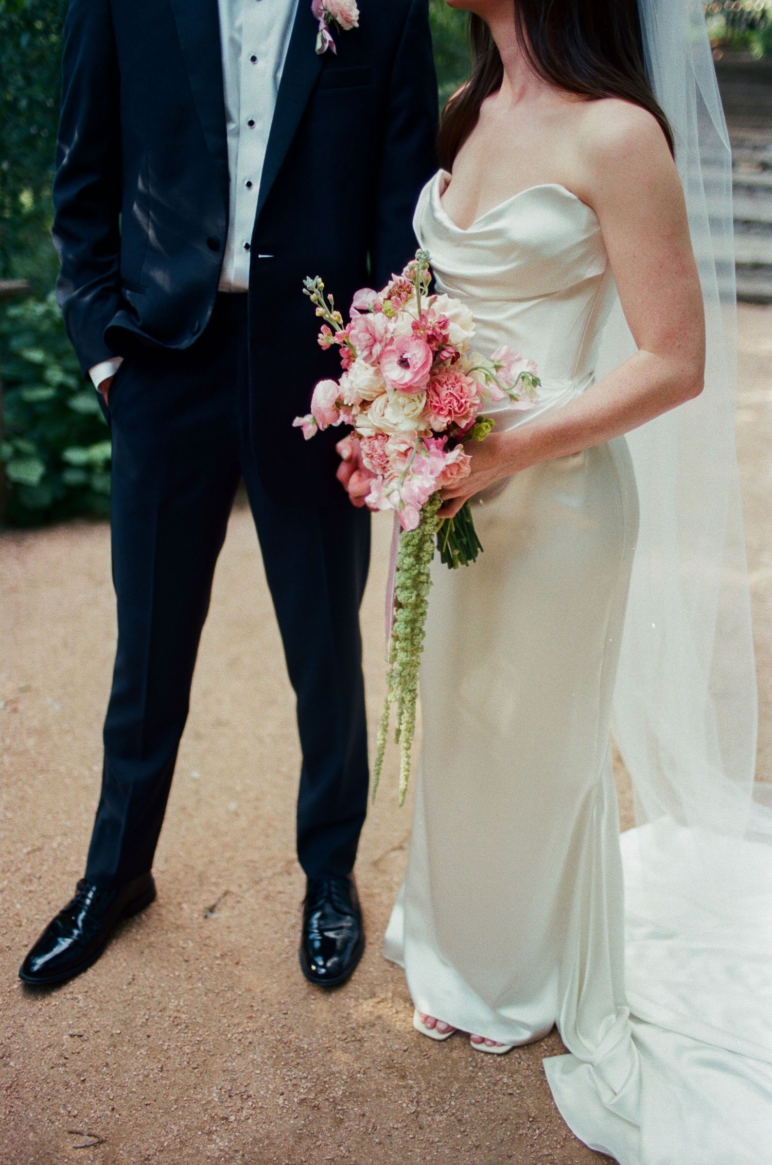 Wedding attire details showing white gown and pink floral bouquet.