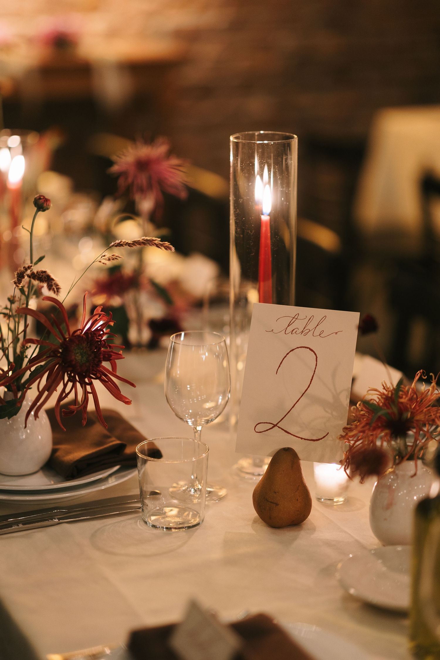 Wedding table details with burgundy floral centerpieces and elegant place settings.