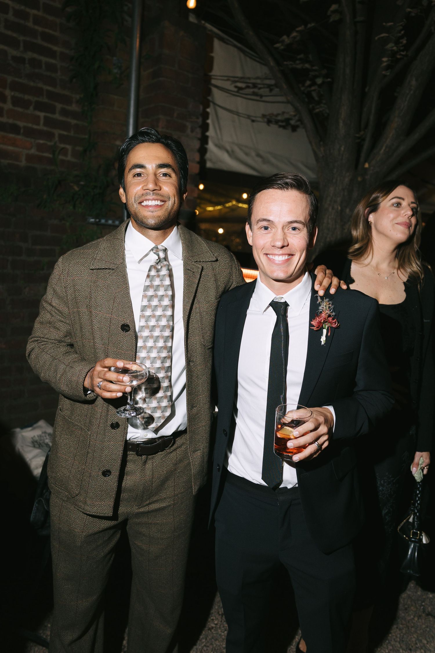 Friends enjoying cocktails and conversation at an evening party with exposed brick walls.