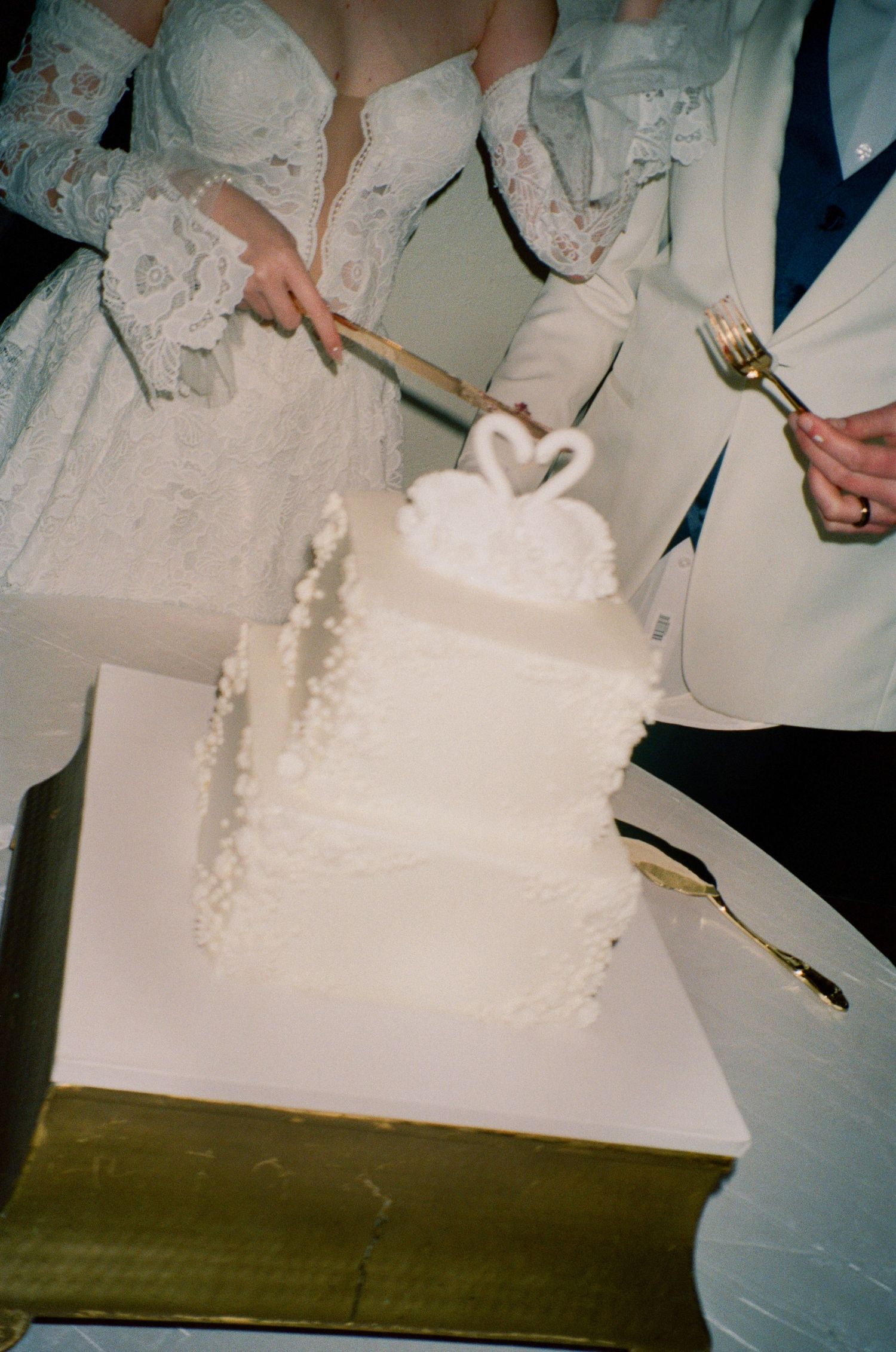 Traditional white wedding cake being cut during the reception ceremony.