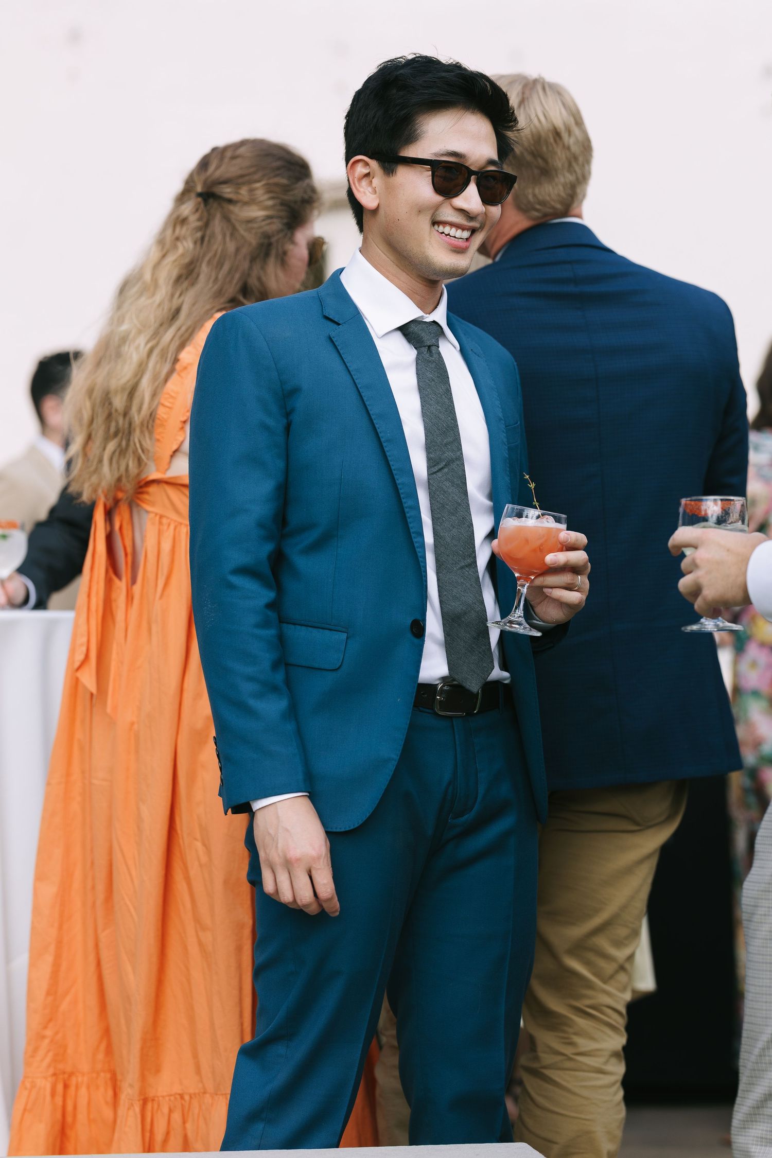 People in formal attire socialize at an outdoor event.