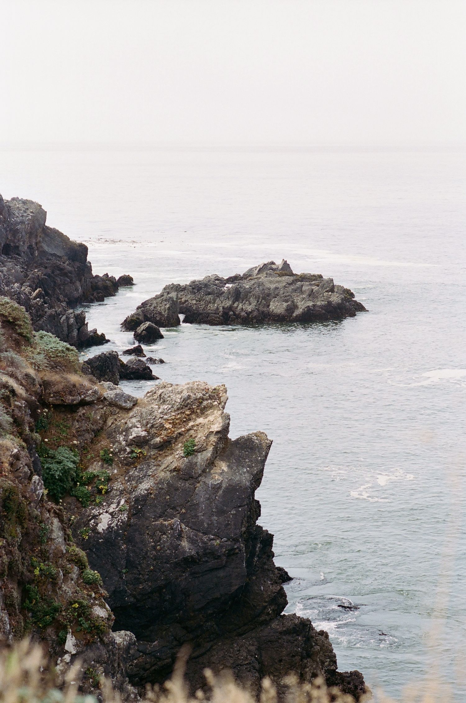 Rocky coastal cliffs overlooking misty ocean waves.