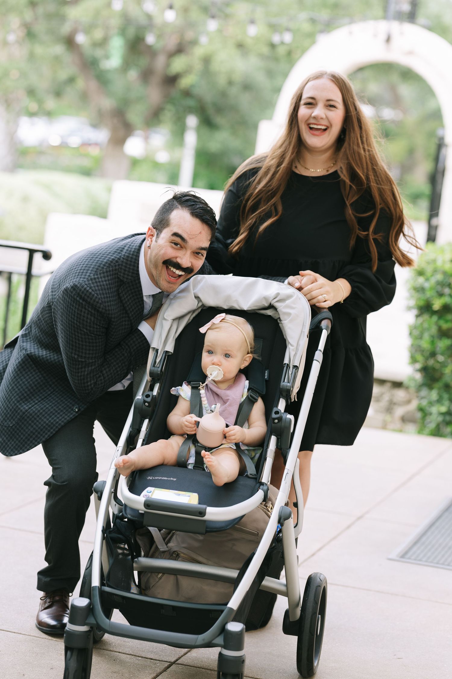Candid moments of guests laughing and interacting with a baby stroller at an outdoor event.