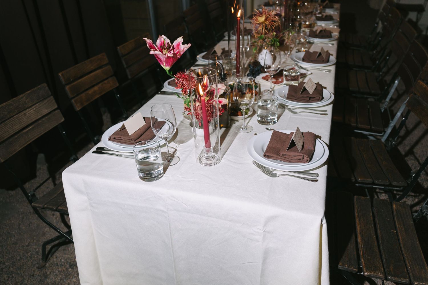 Elegant table settings with floral centerpieces and white linens at a formal dinner.