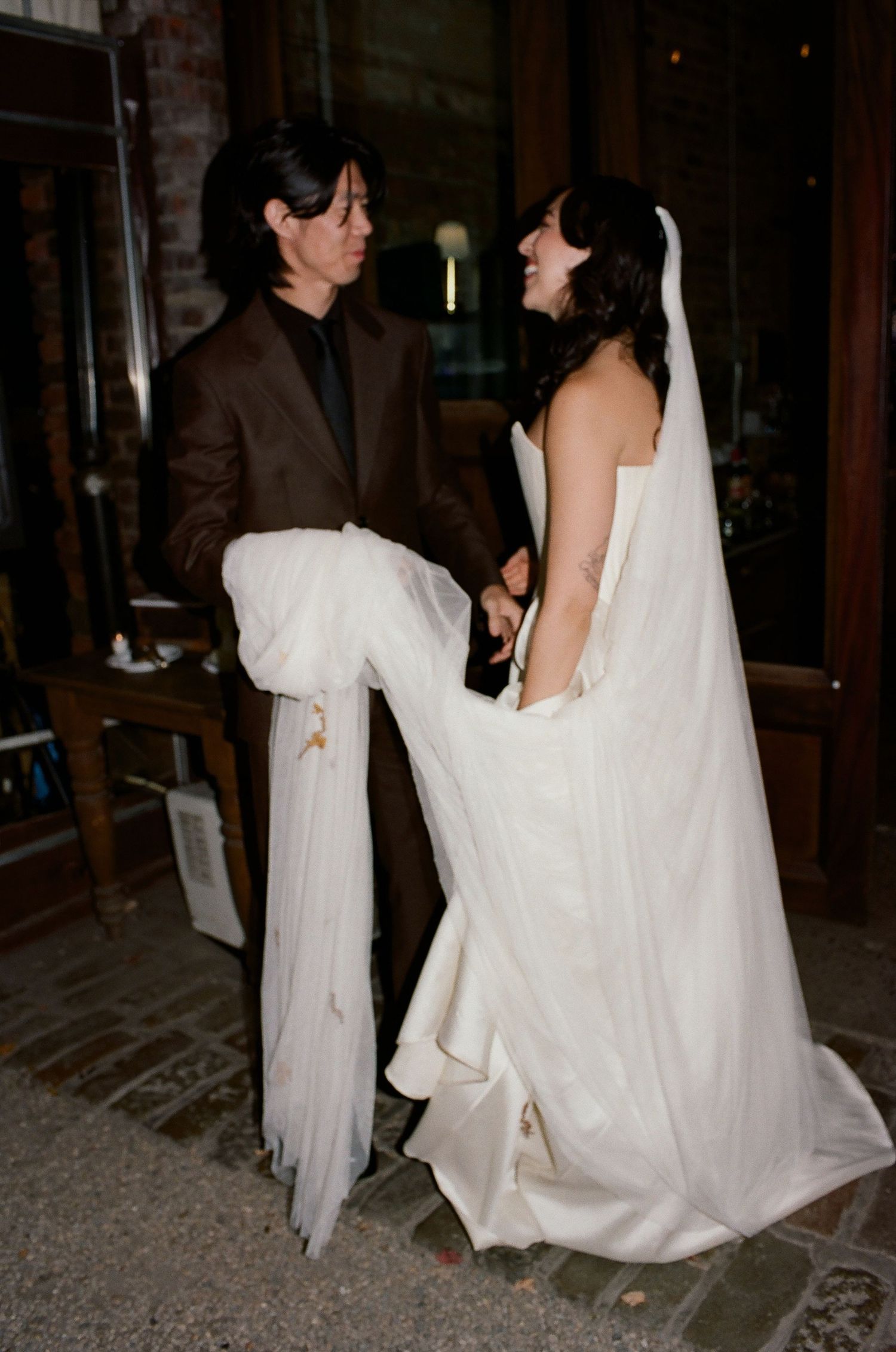 A series of photos showing the flowing movement of a white wedding dress train being carried across a dark floor.
