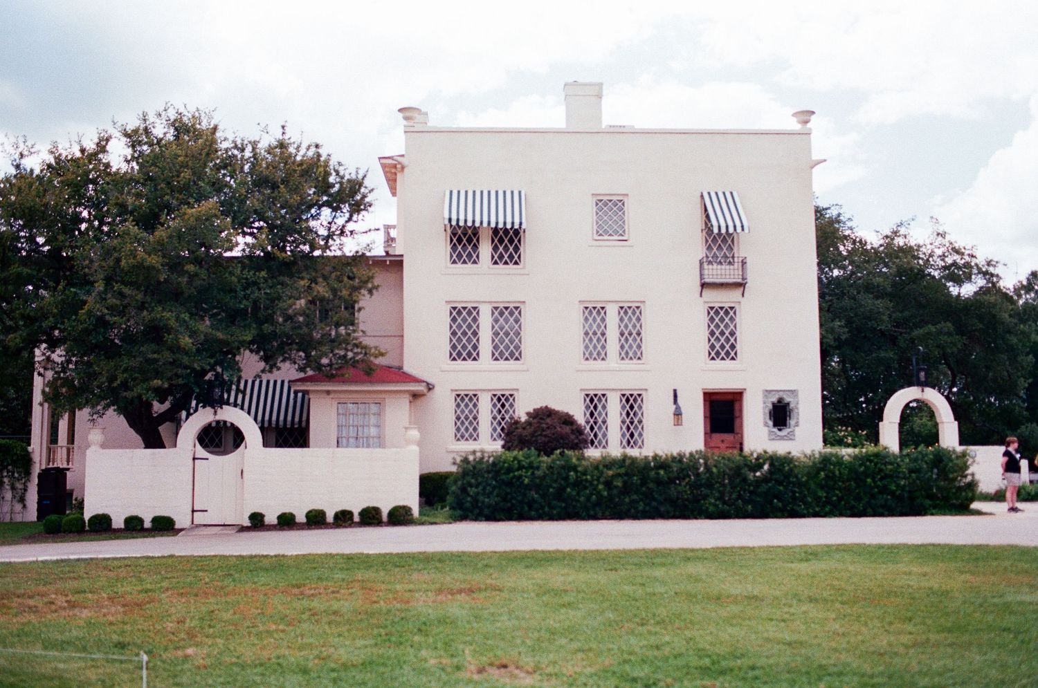 A white Spanish colonial style building with arched windows and manicured lawn.