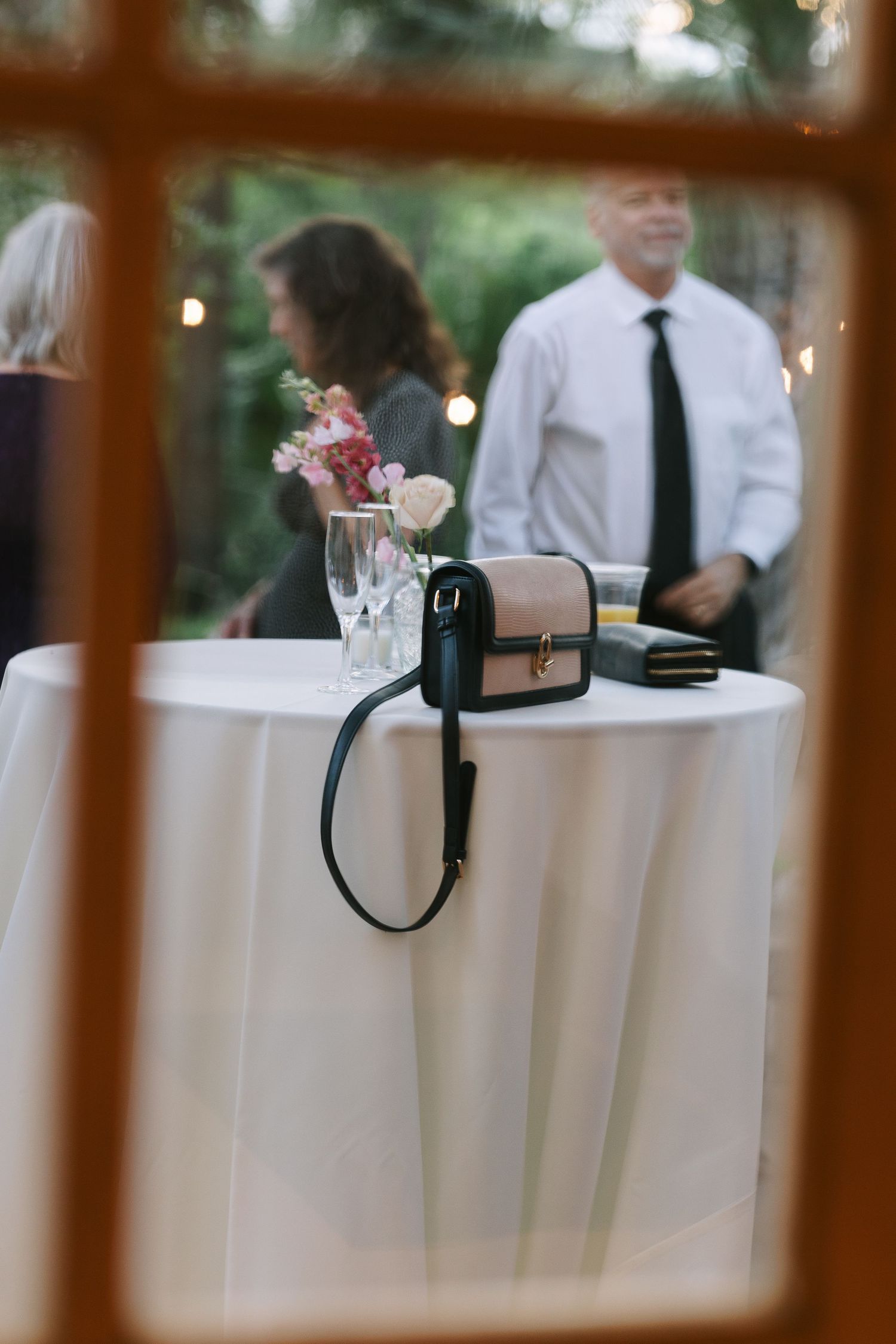 A camera and floral centerpiece sit on a white tablecloth at an outdoor event.