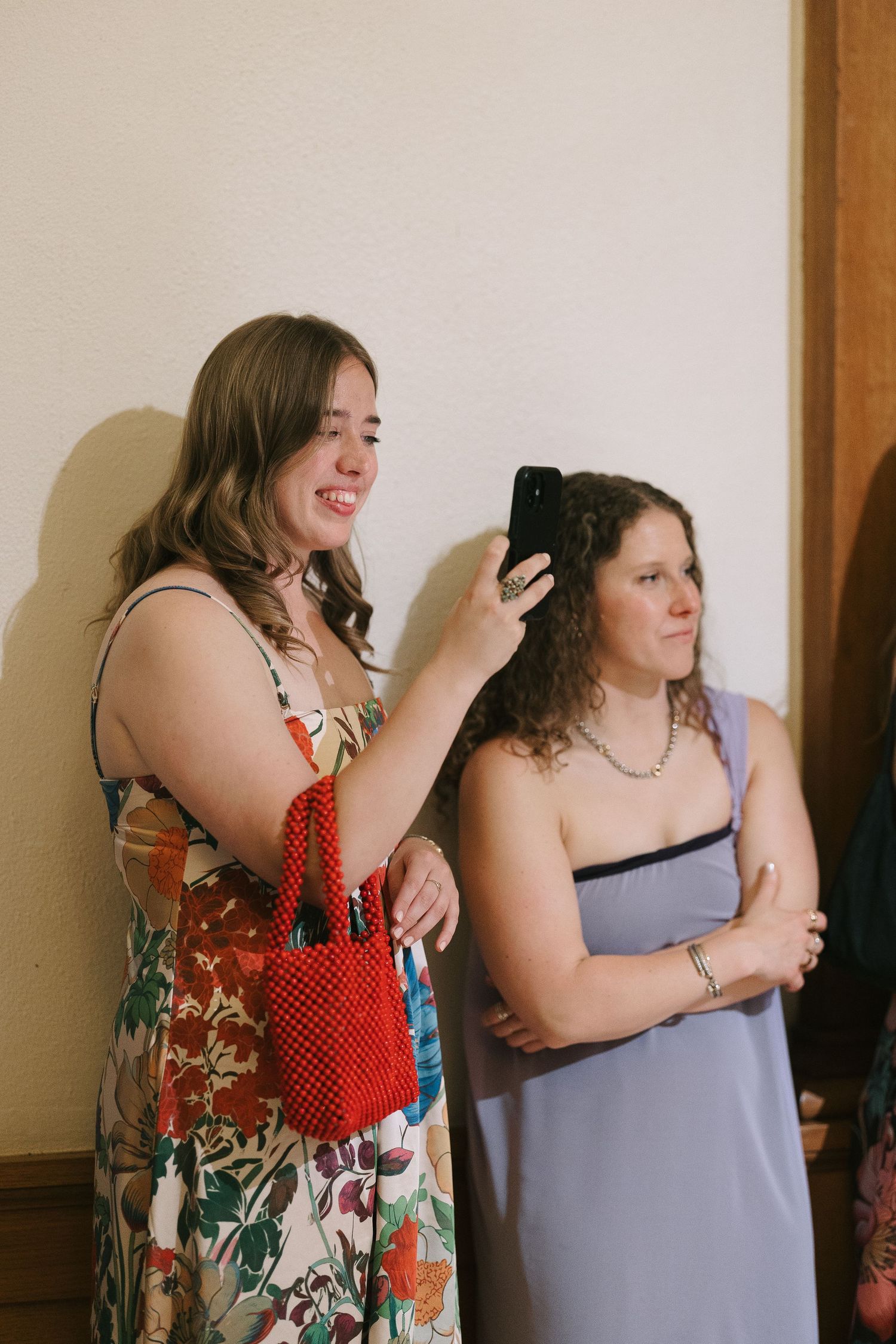A group of women in colorful floral and polka dot dresses pose together at a celebration.