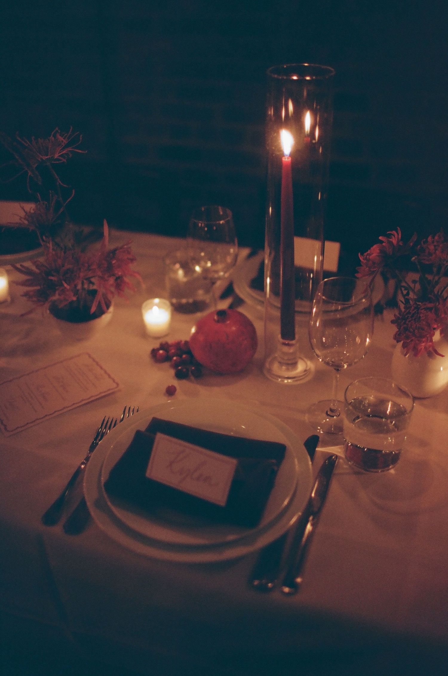 Elegant table setting with candlelight, place card, and autumn decorations for an intimate dinner party.
