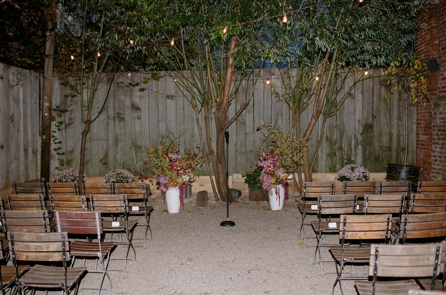Rustic outdoor patio area with wooden benches and string lights creating a cozy garden atmosphere.