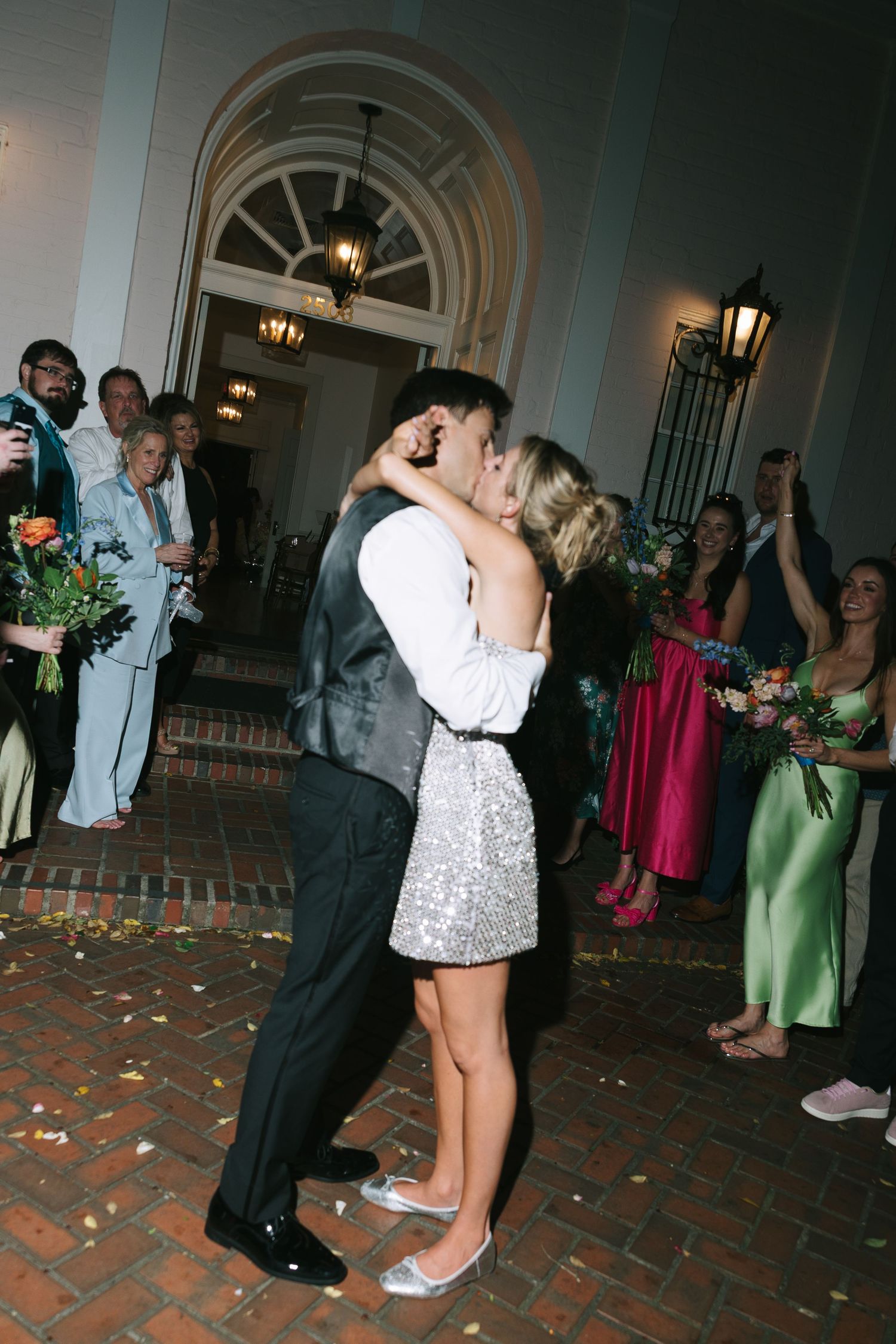 A romantic kiss shared during a wedding reception as guests look on.