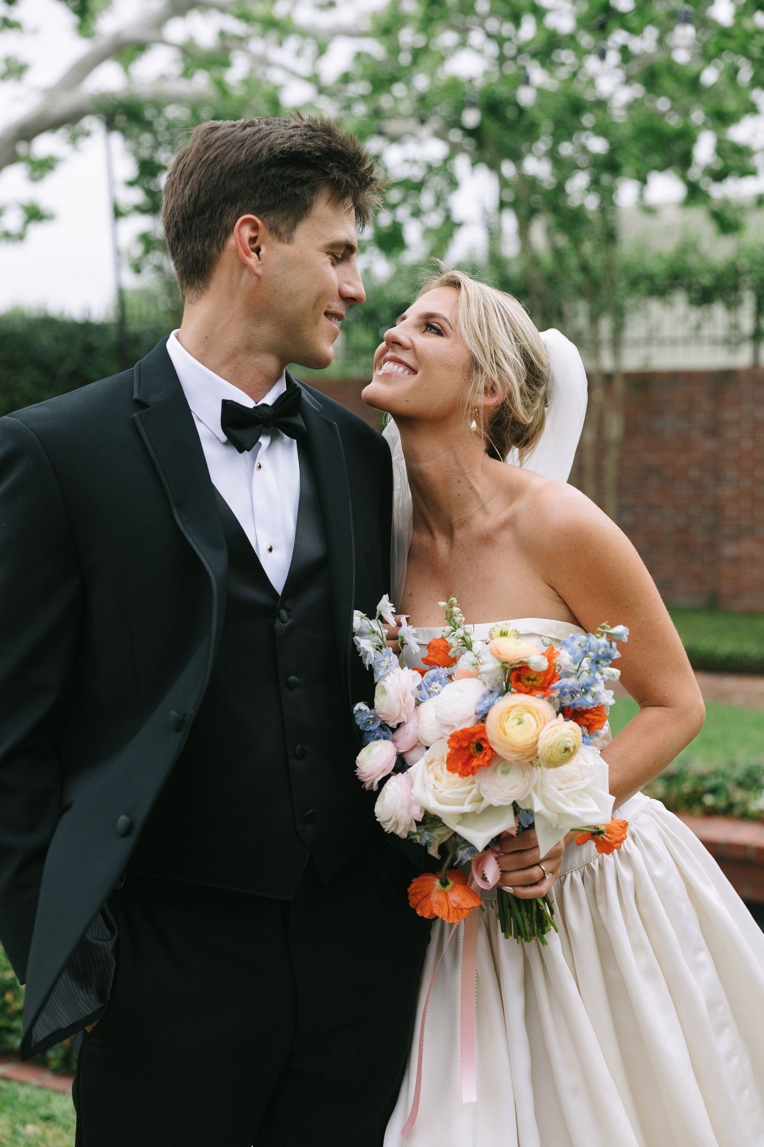 Newlyweds share joyful moments together outdoors with a beautiful floral bouquet.