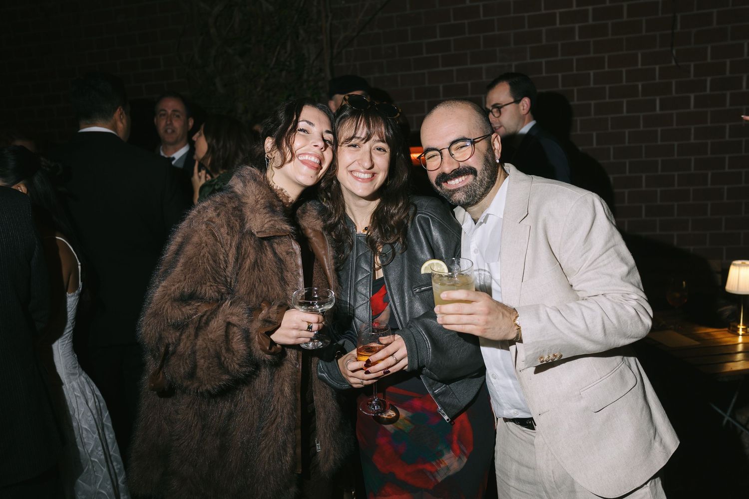 Group of party guests socializing and drinking at an indoor evening event.