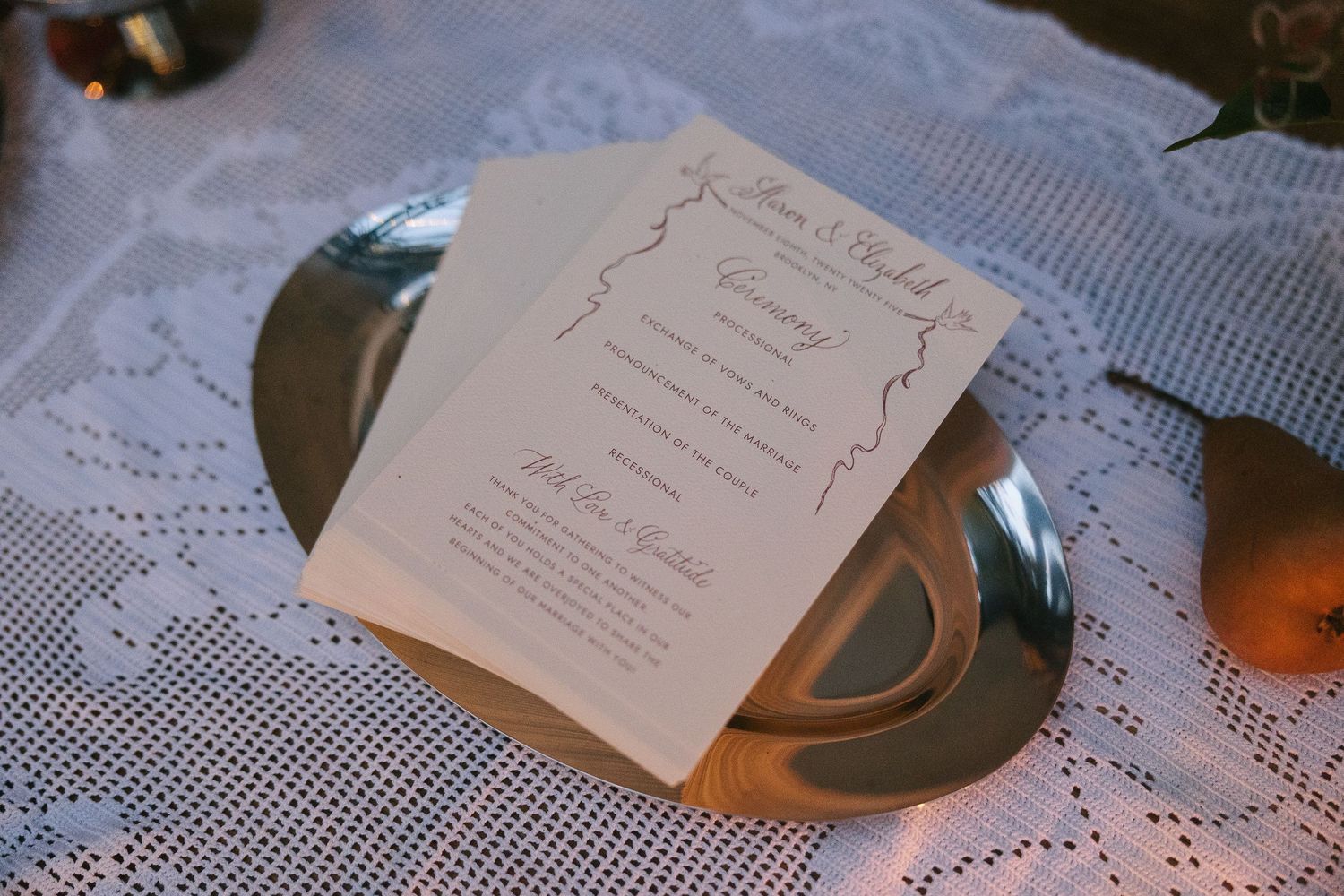 Wedding stationery and paper goods arranged on lace tablecloth with elegant details.