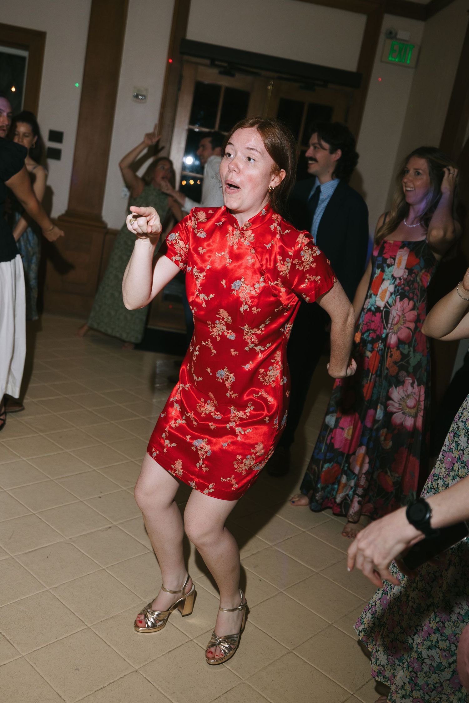Wedding guests dancing and having fun on a tiled floor during reception.