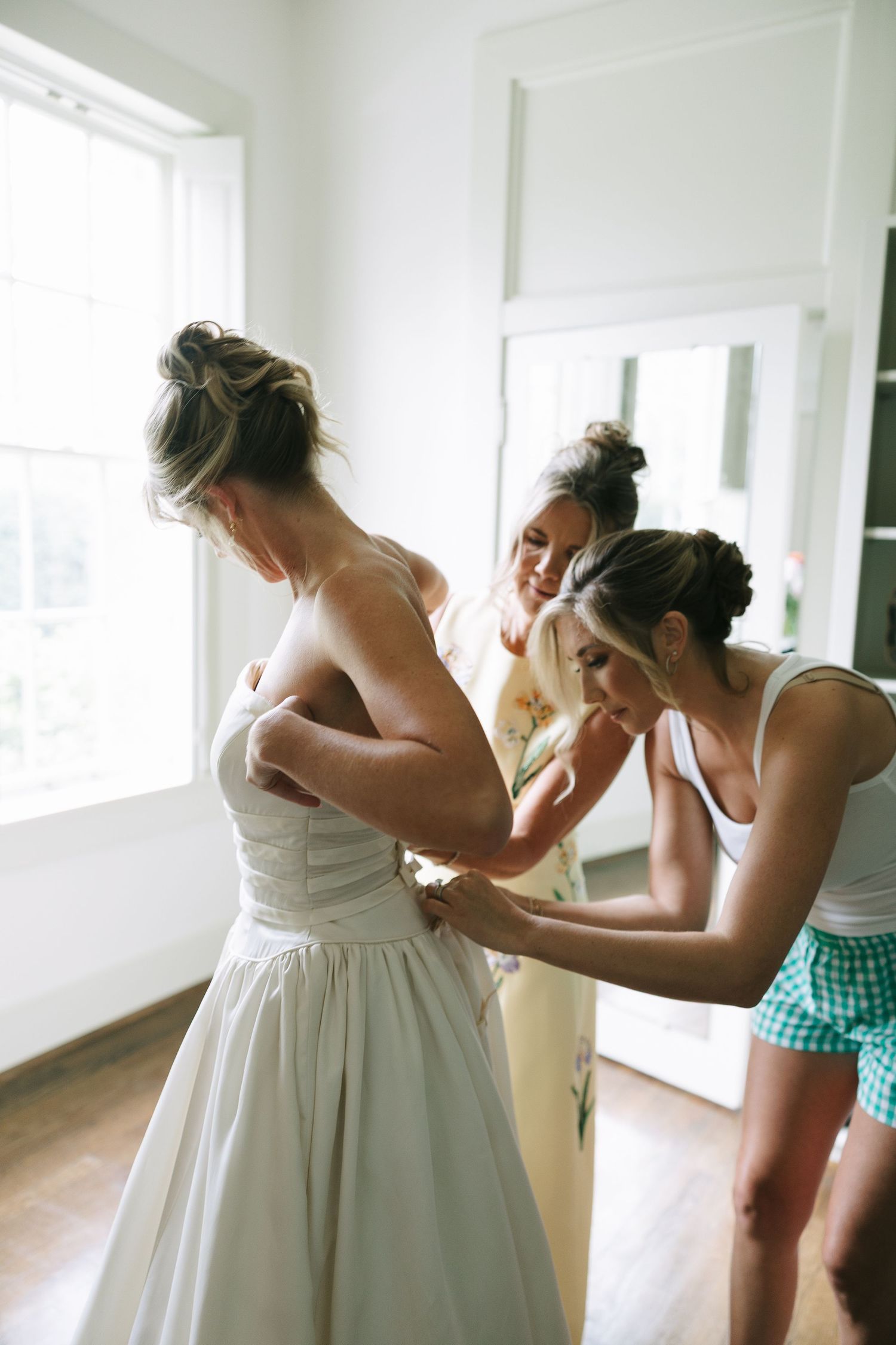 Wedding dress fitting and adjustments in a bright indoor space.