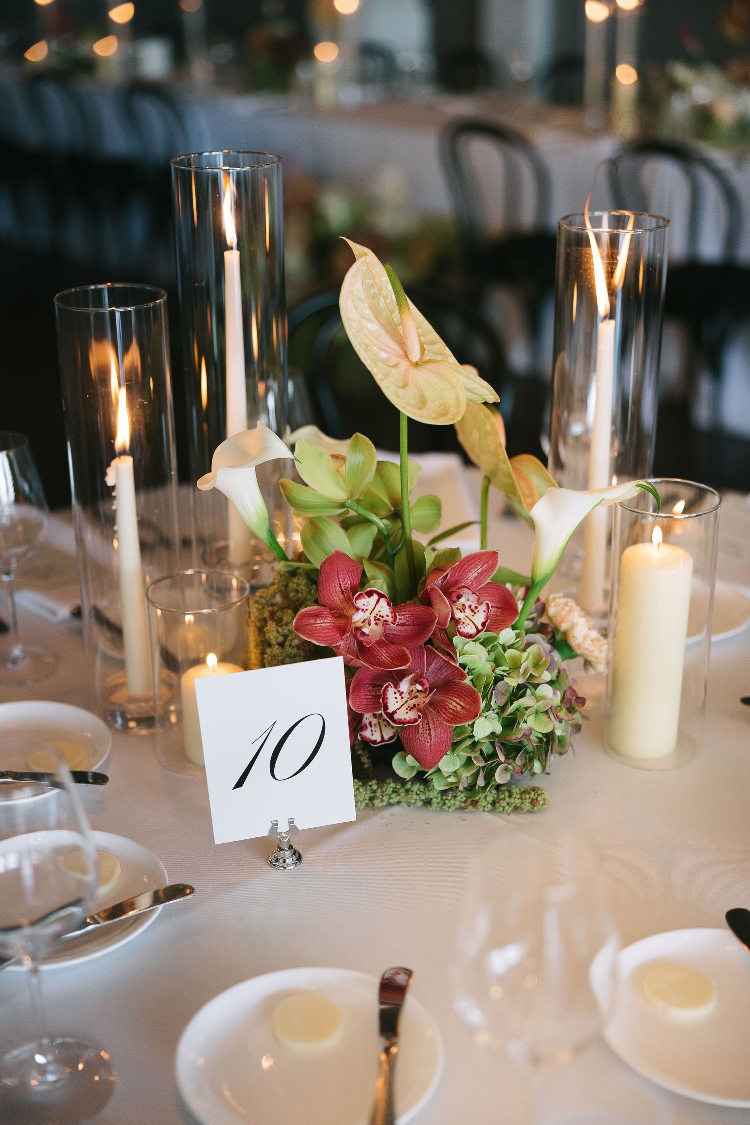 Romantic table setting with white candles, floral arrangements and table number cards.