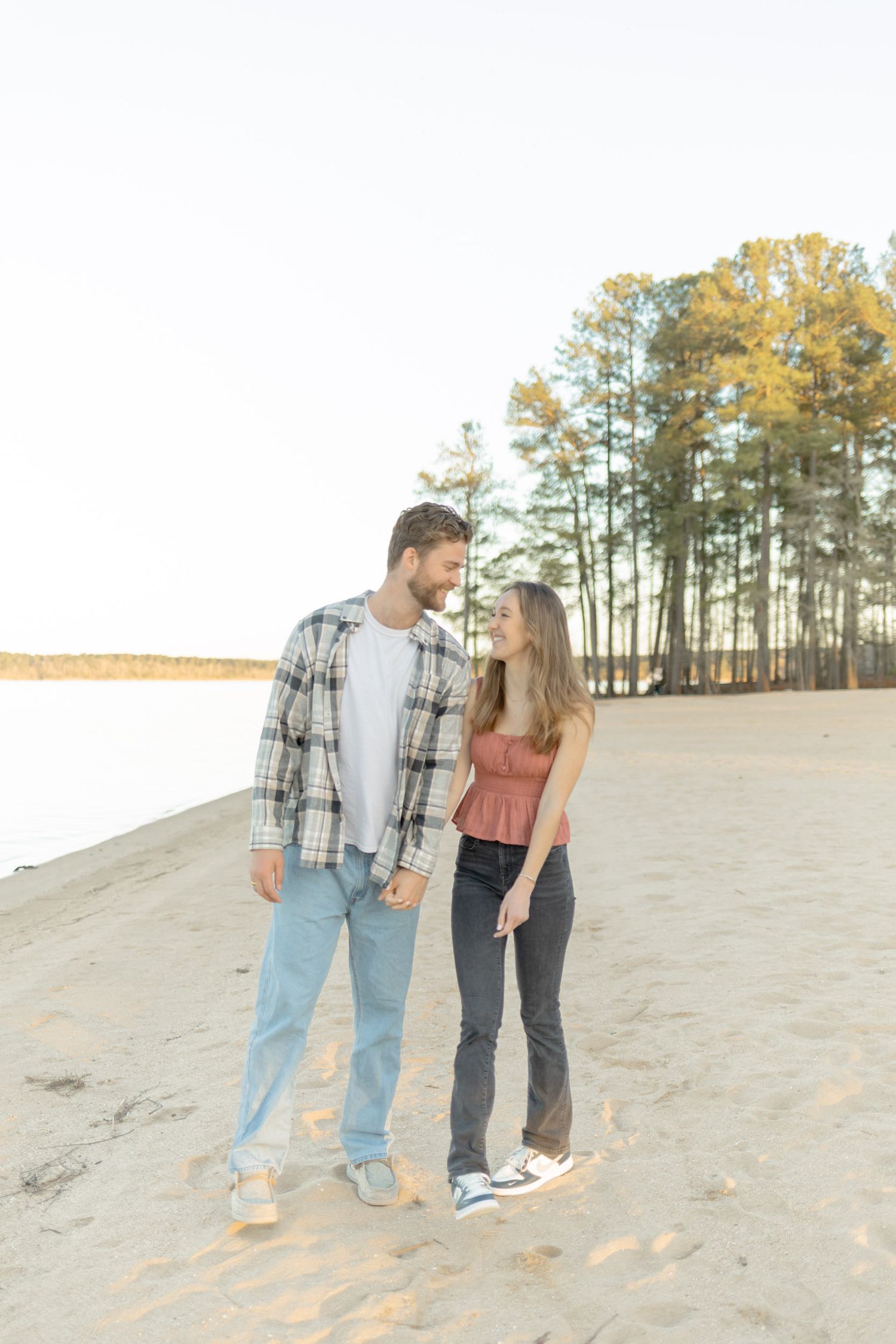Couple walking together on sandy slope during sunset with pine trees in background in Raleigh, North Carolina.