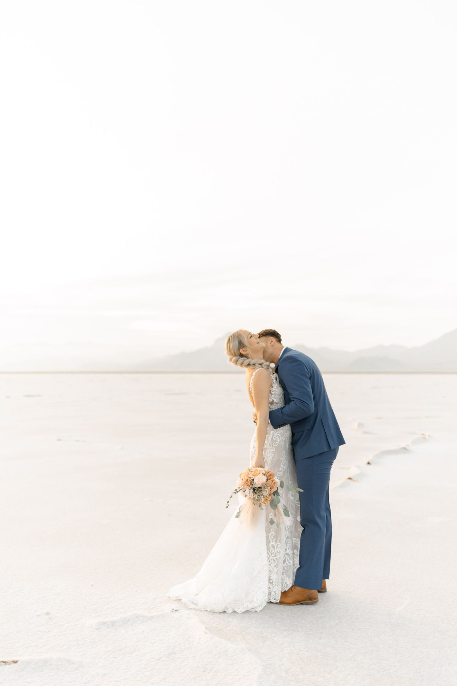 Romantic wedding couple shares an intimate moment on a bright white sandy beach.