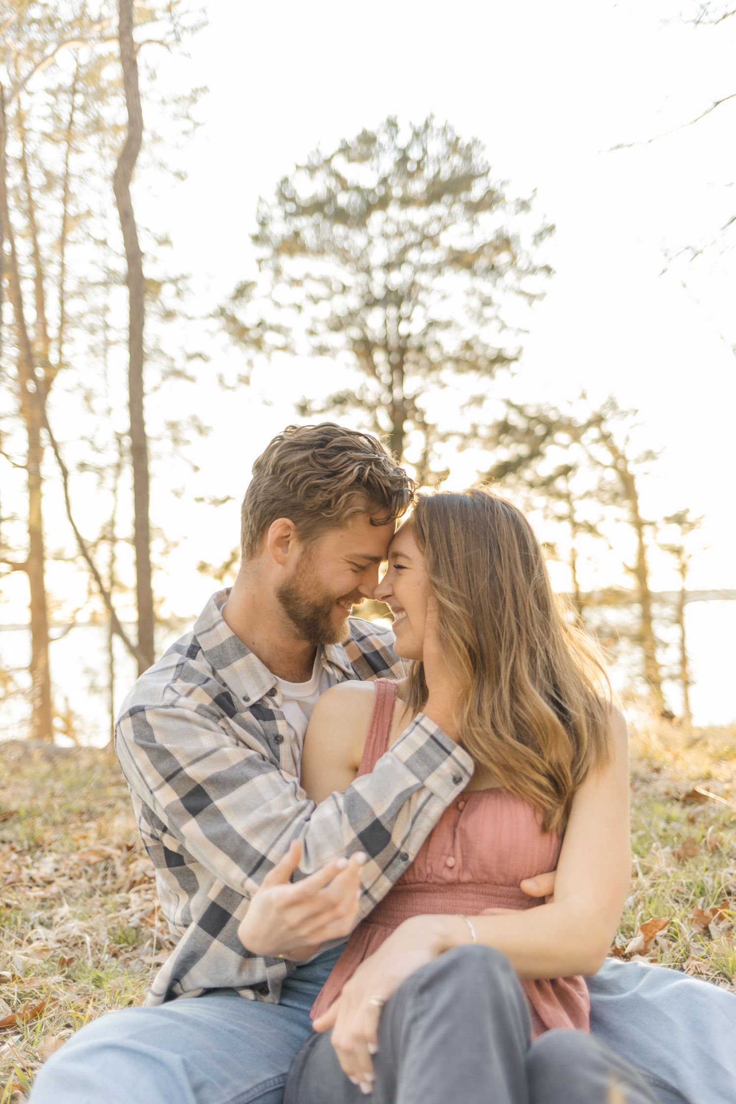 Intimate moment between couple sitting in autumn forest during sunset in Raleigh, North Carolina.