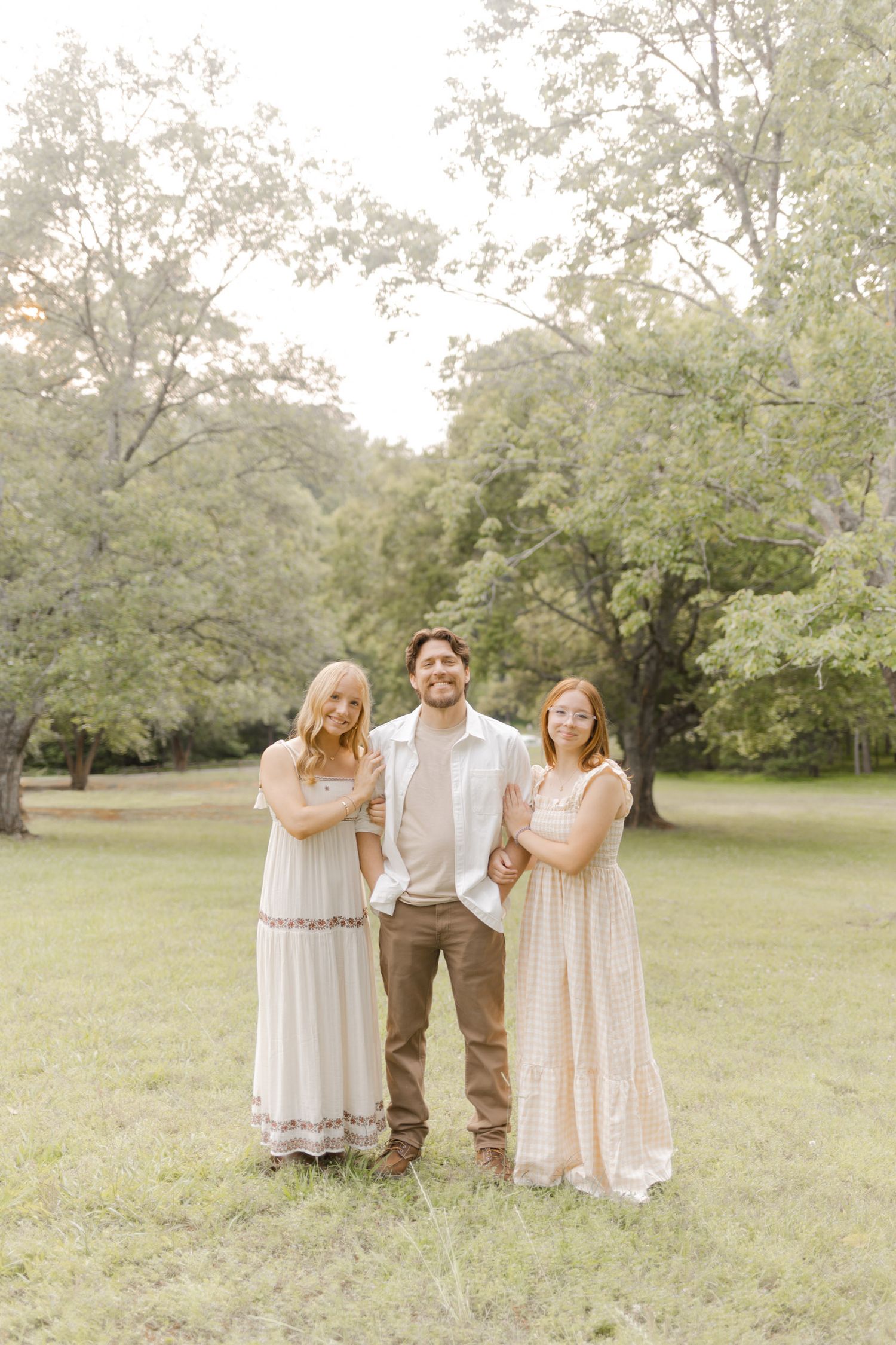 A group poses casually together in coordinated neutral outfits in a sunny park setting with Durham, North Carolina Photographer.