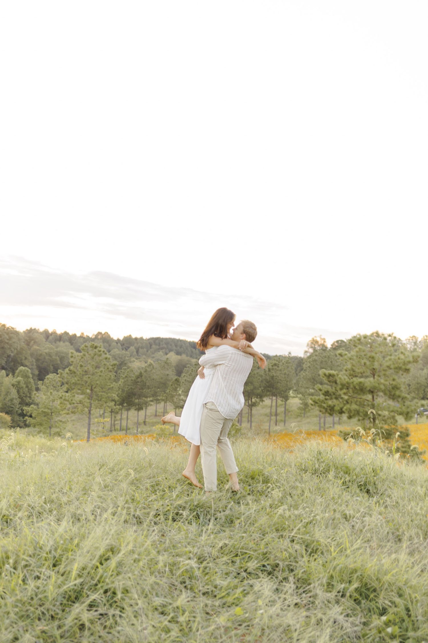 Romantic dance in a sunlit meadow with rolling hills in background during engagement session in Chapel Hill, NC.