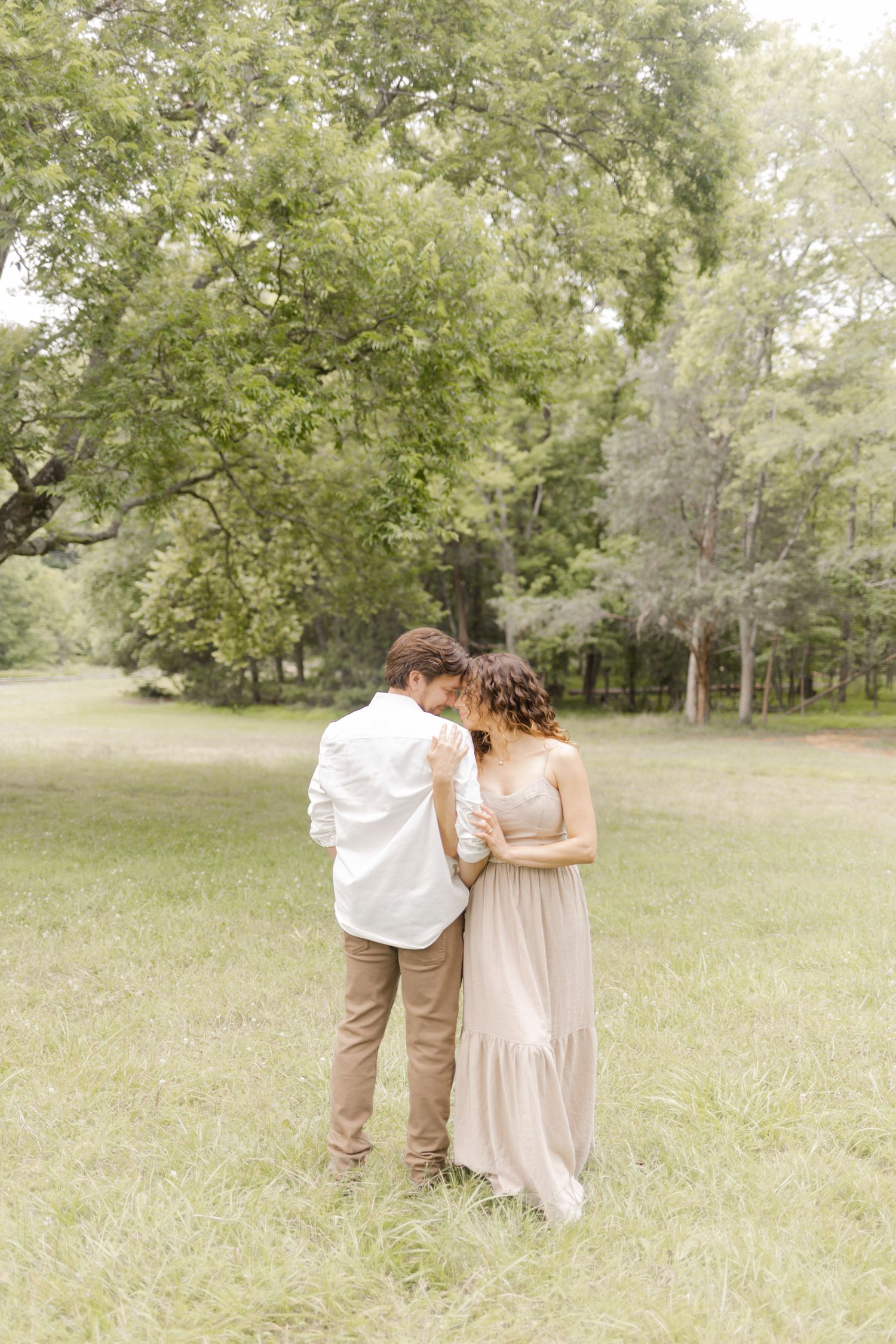 Two people walk close together across a grassy field on a bright summer day in Durham, North Carolina.