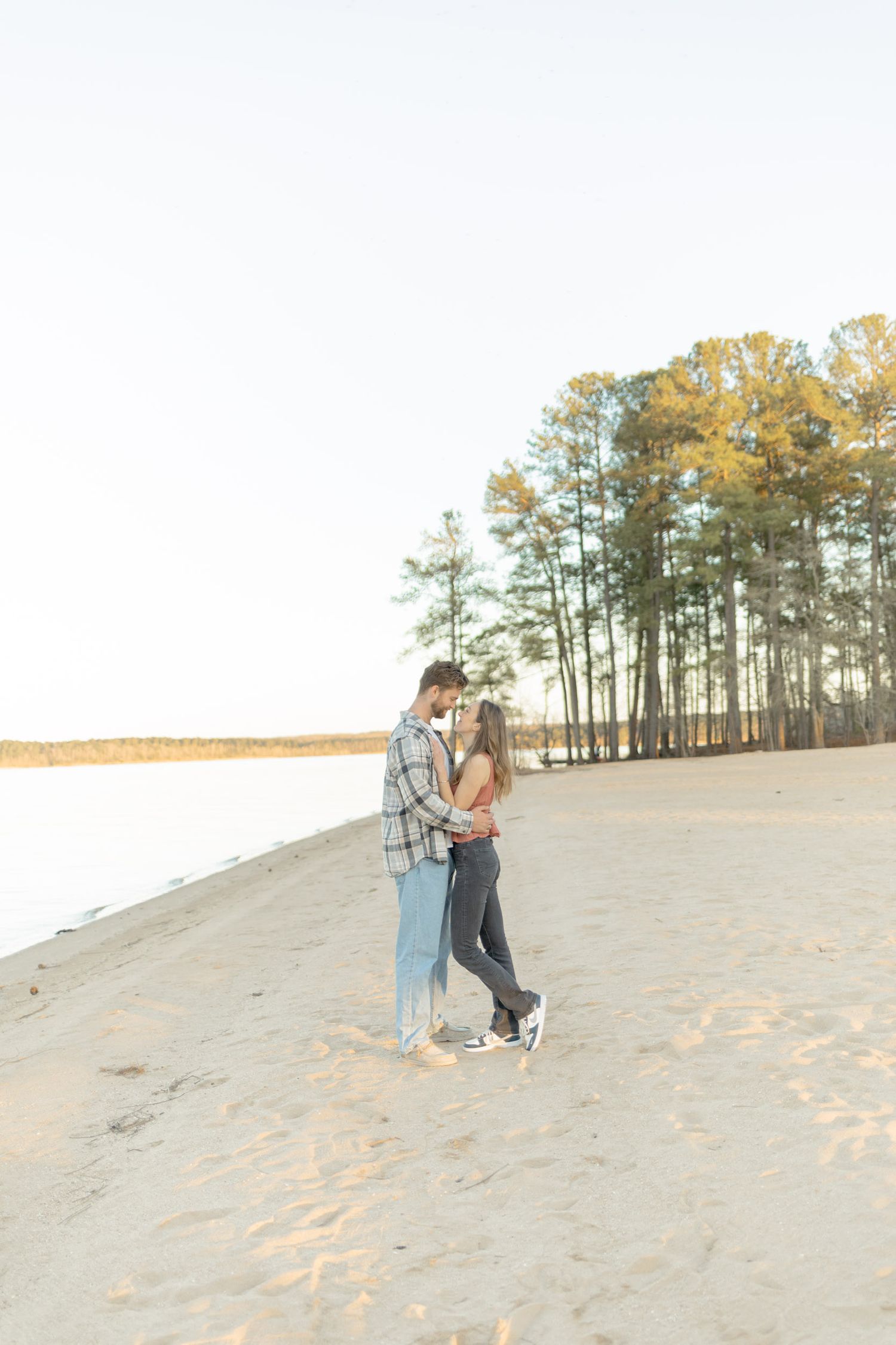 Couple strolling together on a sandy slope with pine forest backdrop during photoshoot with Kinsley Nicole Photography.