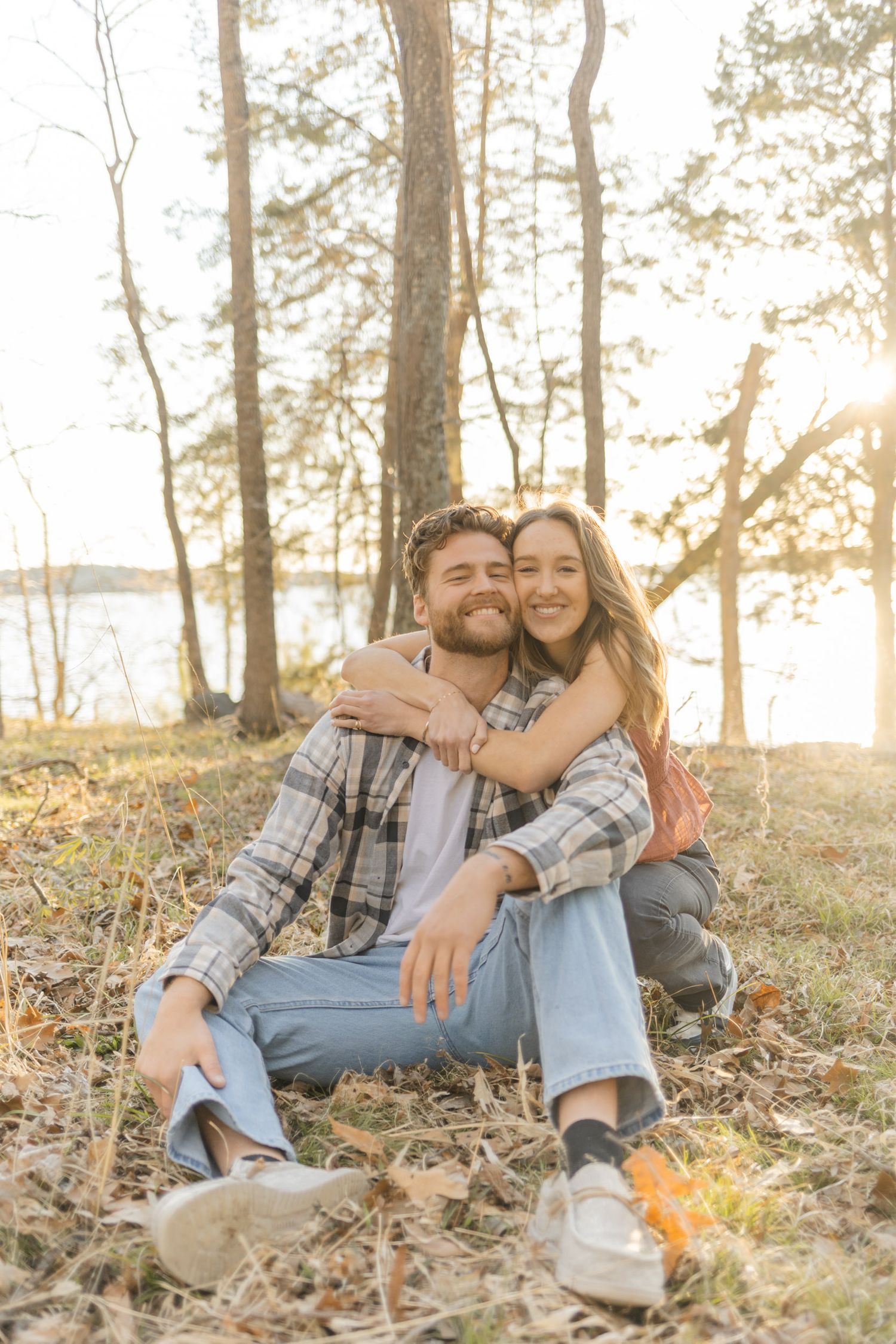 Candid moment of couple laughing together on forest floor during golden hour in Raleigh, North Carolina.