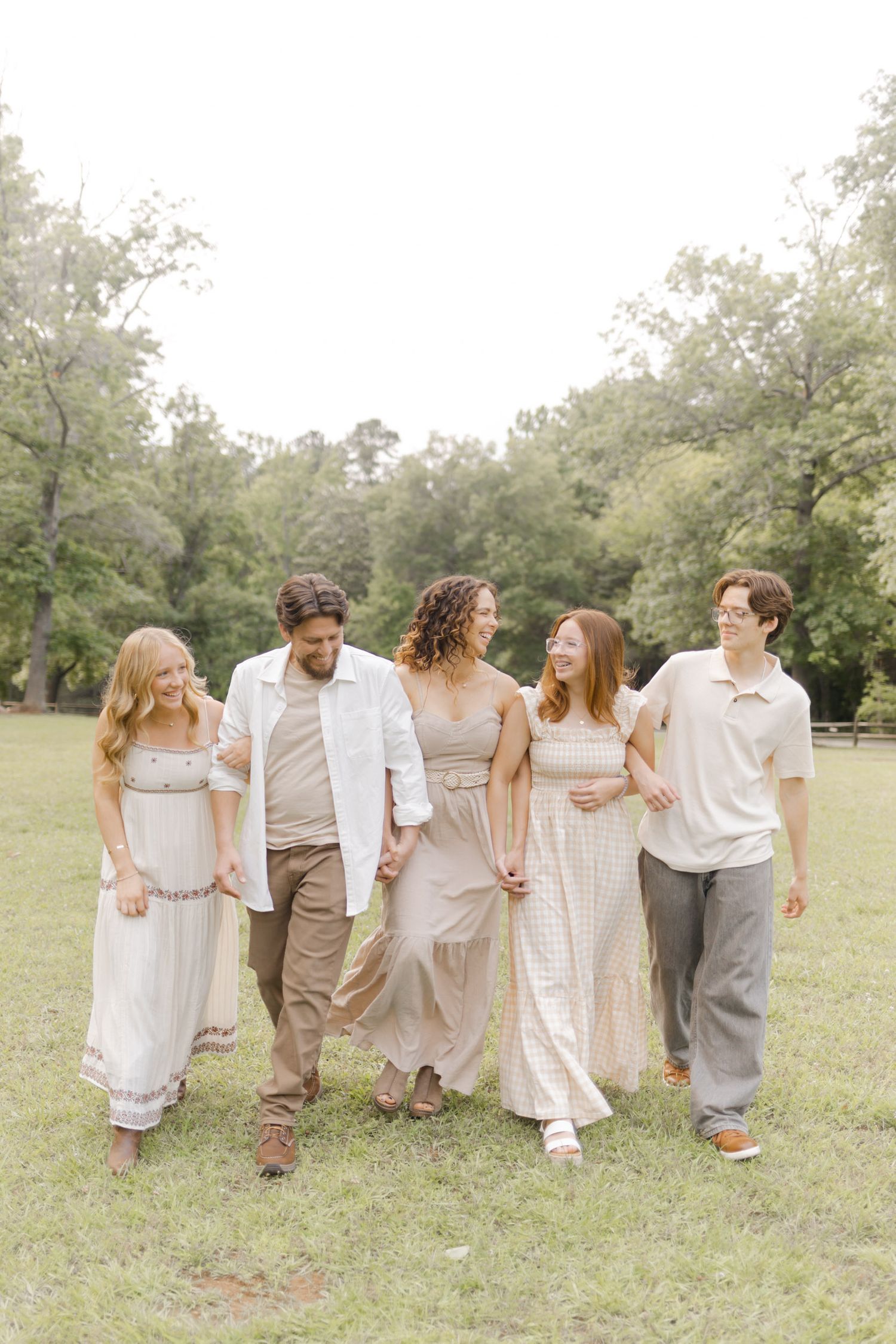 Group walking together in coordinated neutral outfits captured from behind in a park setting during photoshoot with Kinsley Nicole Photo