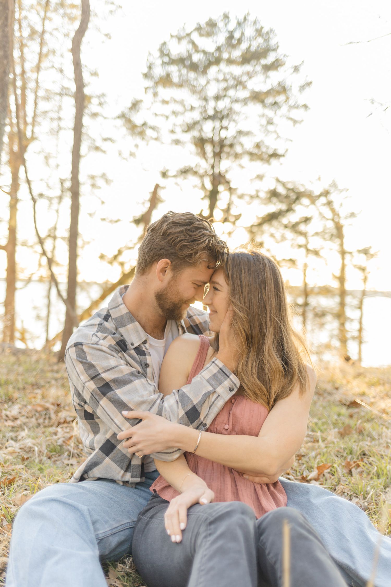 Couple sharing tender moments while sitting on a blanket in a natural outdoor setting during photoshoot with Kinsley Nicole Photography.