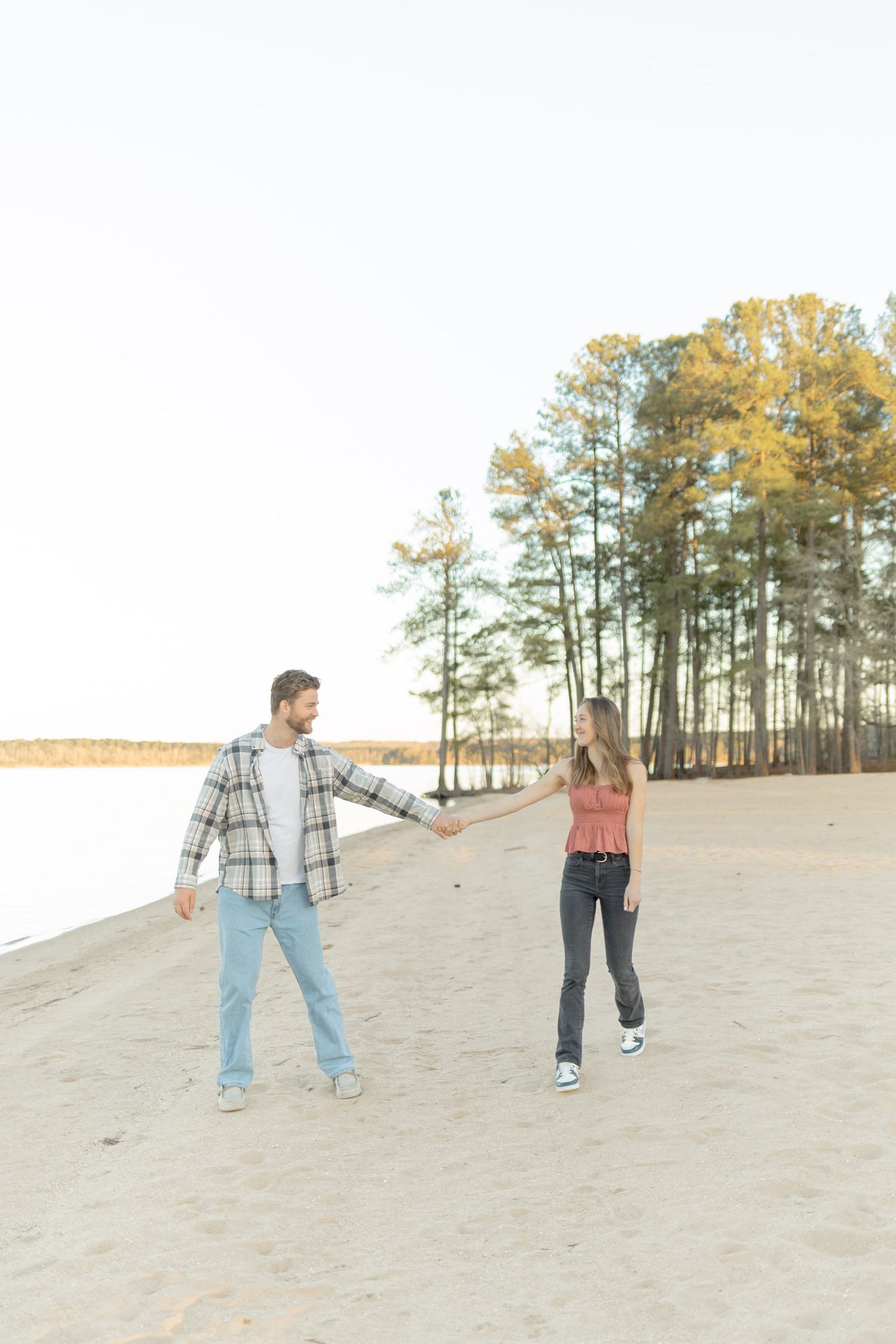 Two people dancing and having fun on a sandy beach during sunset making a light, airy, creamy photo in Raleigh, North Carolina.