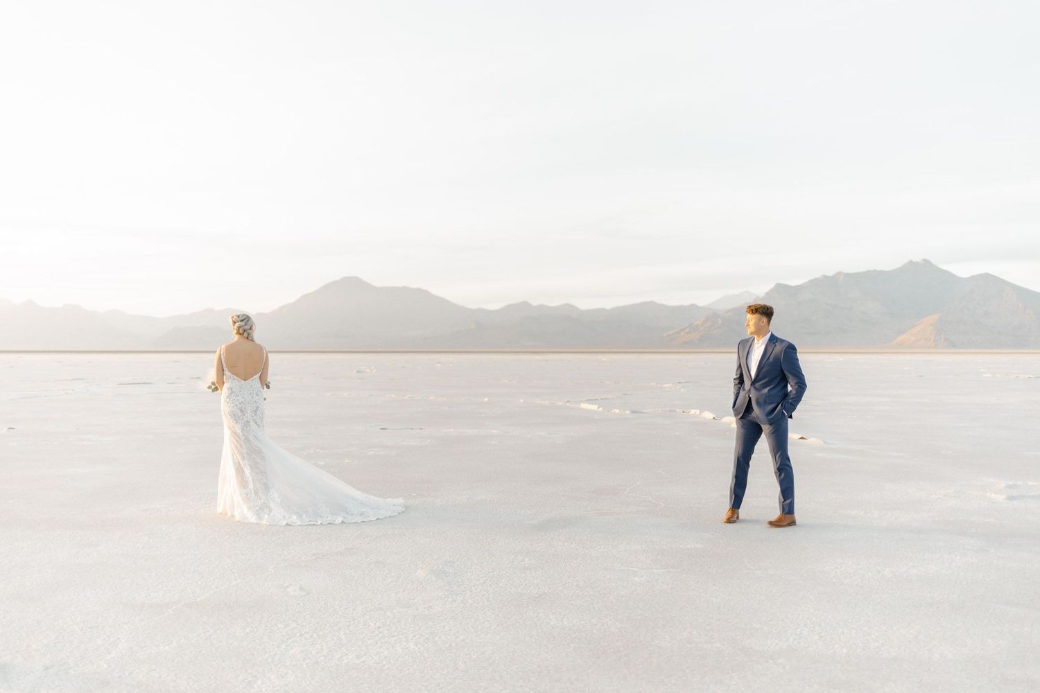 Wedding photography session on expansive salt flats with distant mountains and soft lighting.