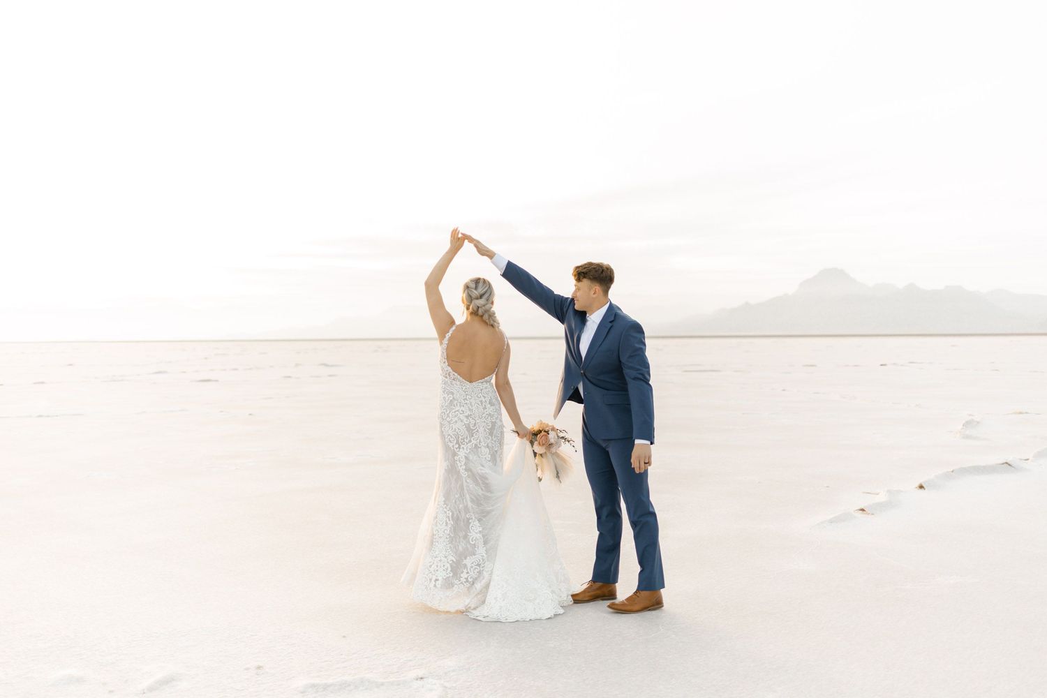 A couple in wedding attire walks along a pristine white sand beach during their romantic beachfront photo session.