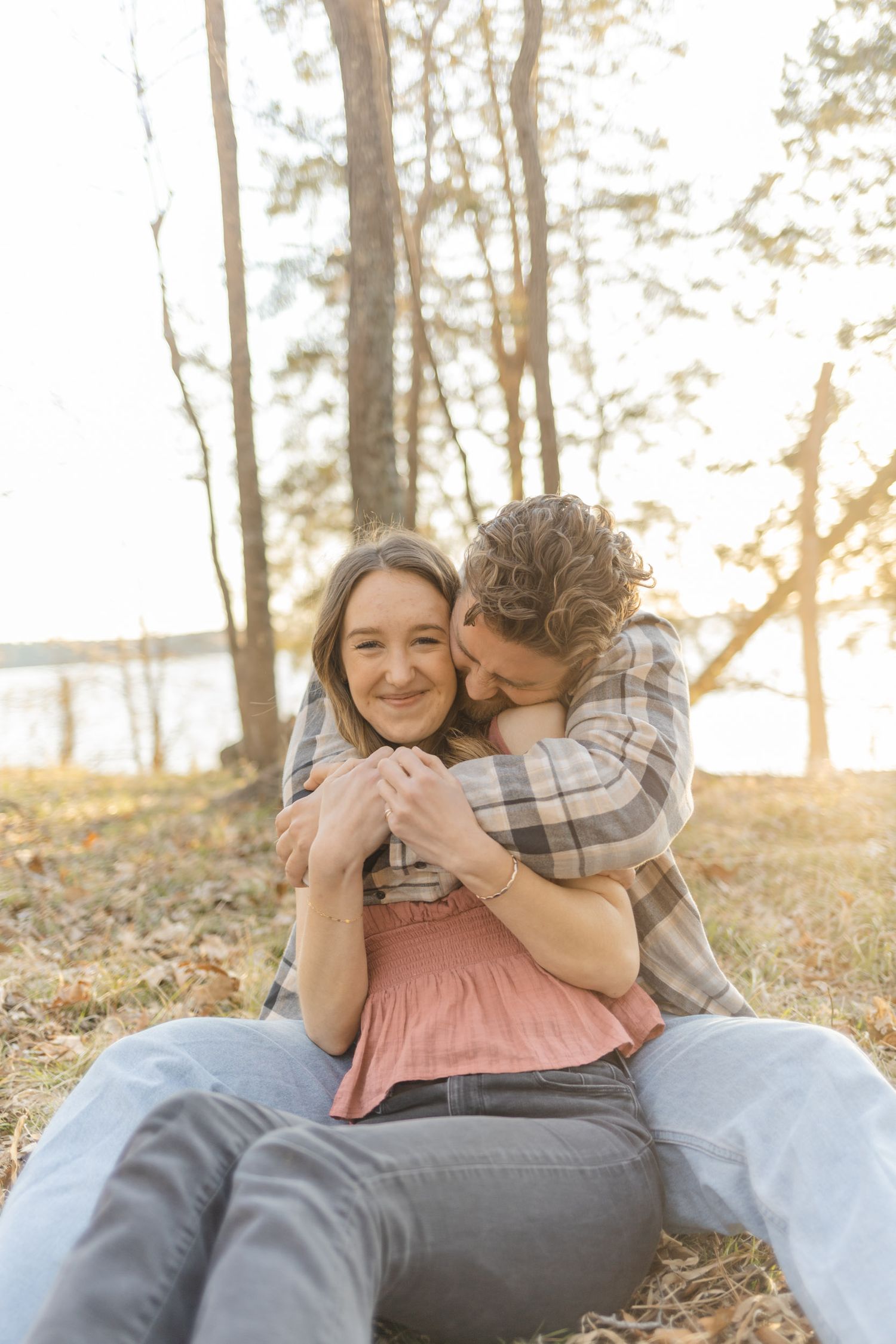 A romantic couple shares intimate moments while laying on a blanket in a sunlit forest setting in Raleigh, North Carolina.