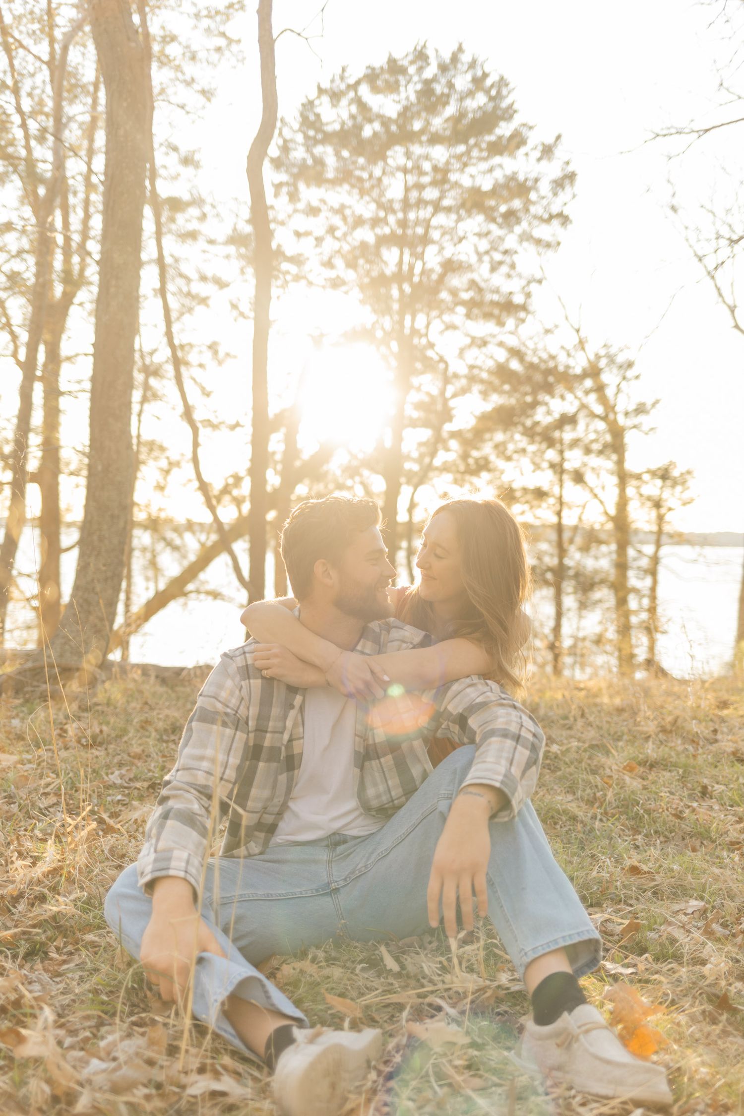 Couple relaxing on fallen leaves in a forest during golden hour during photoshoot with Kinsley Nicole Photography.