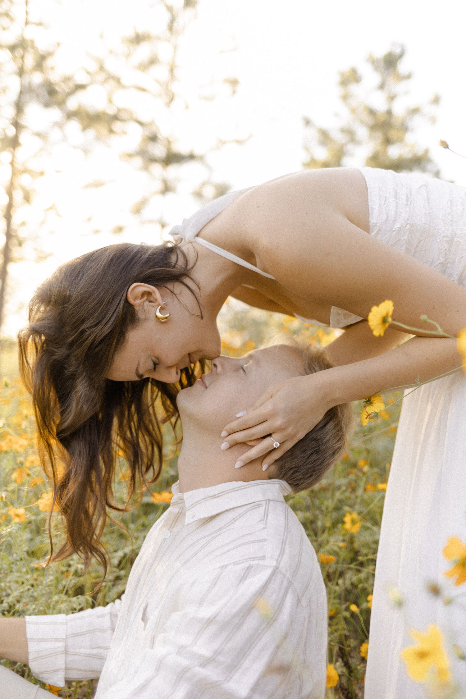 Woman in white dress bending gracefully among yellow wildflowers at golden hour during lifestyle portrait photoshoot.
