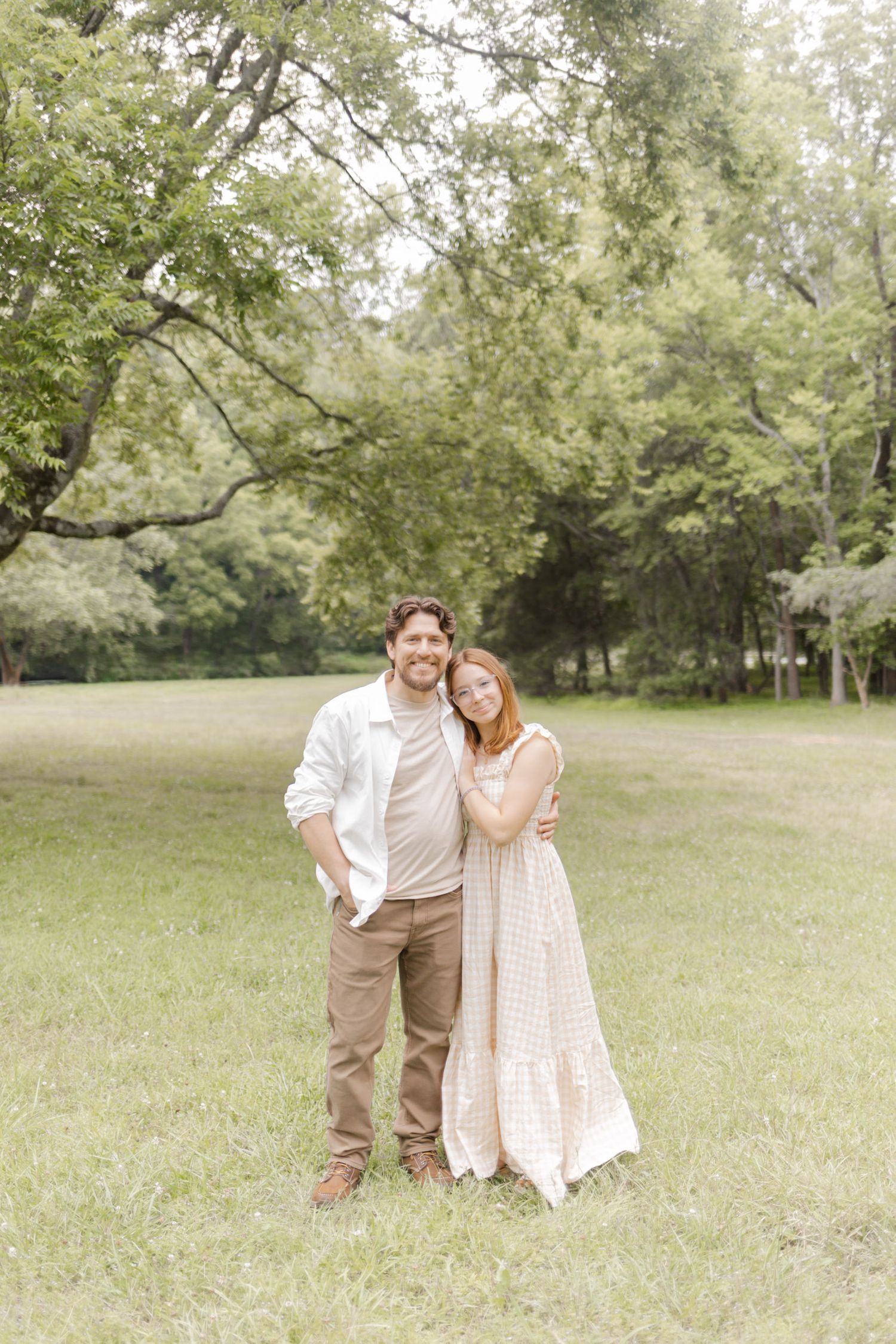A romantic photoshoot in a green meadow with a couple wearing cream and white outfits during photoshoot in Durham, NC.