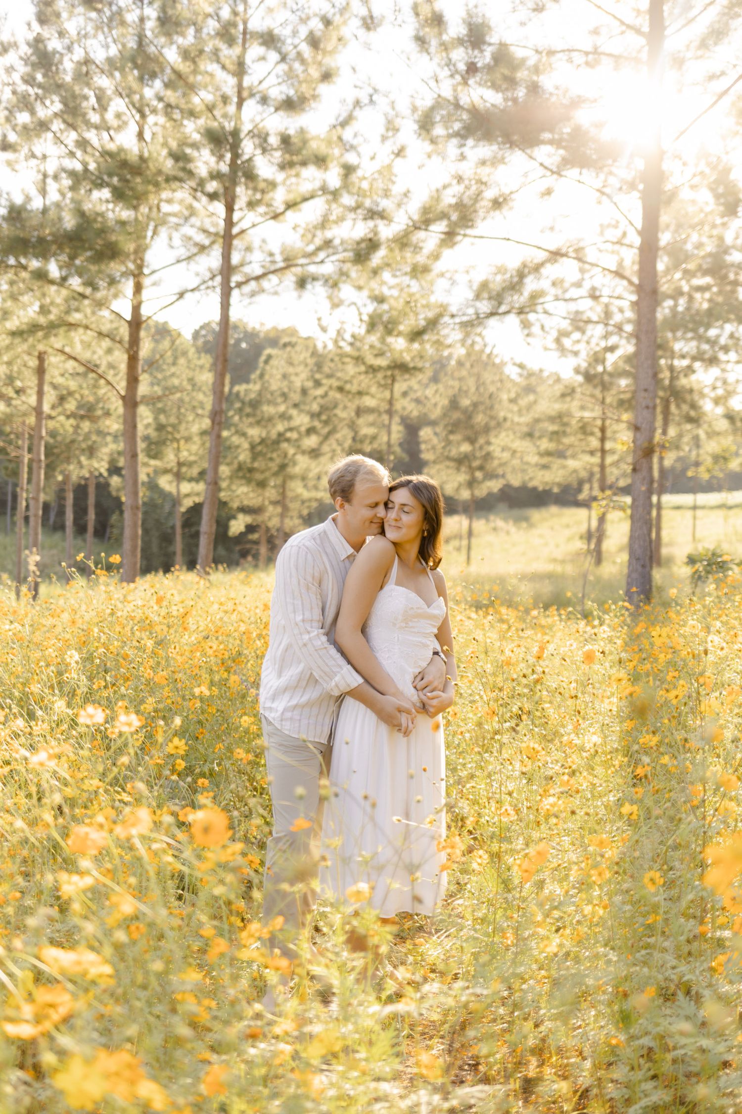 A romantic embrace in a field of yellow wildflowers during golden hour at photoshoot in Chapel Hill