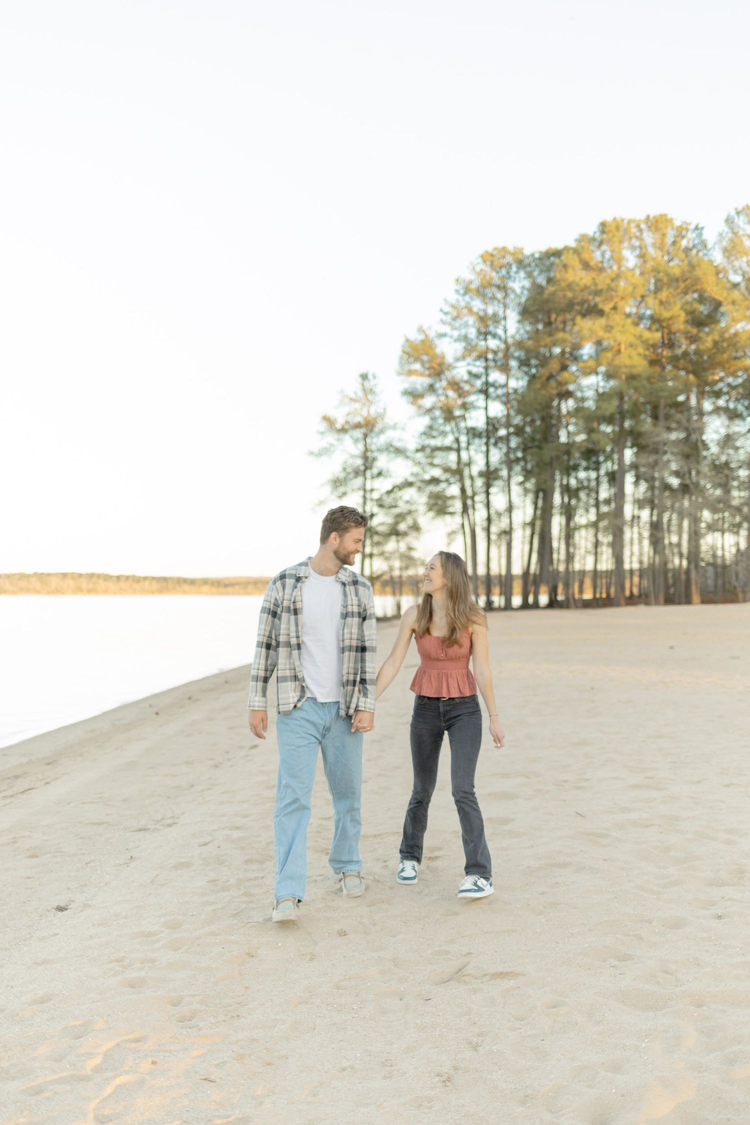 Couple exploring sandy terrain together with evergreen forest in background in Raleigh, North Carolina.